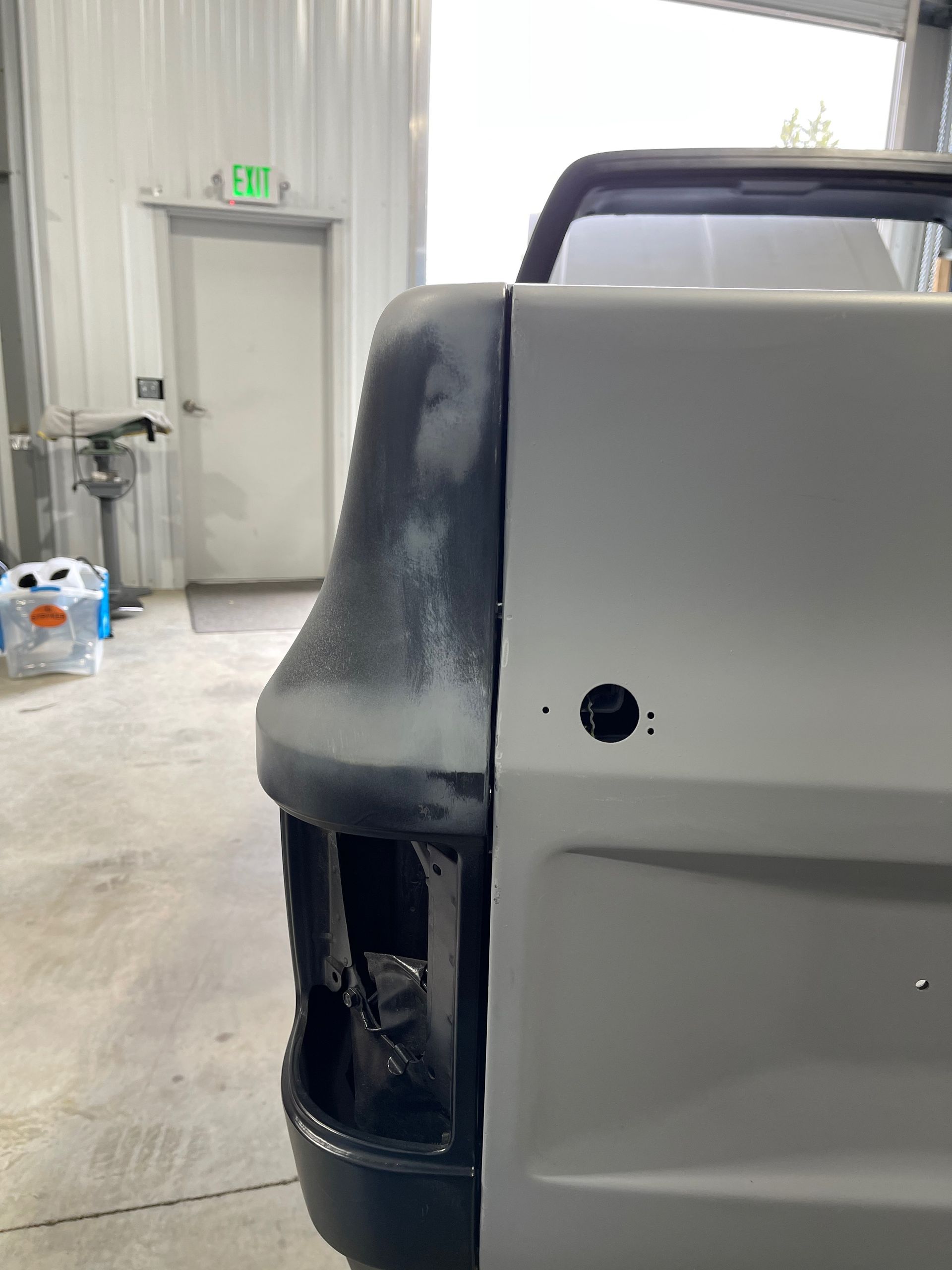 The back of a truck is being painted in a garage.