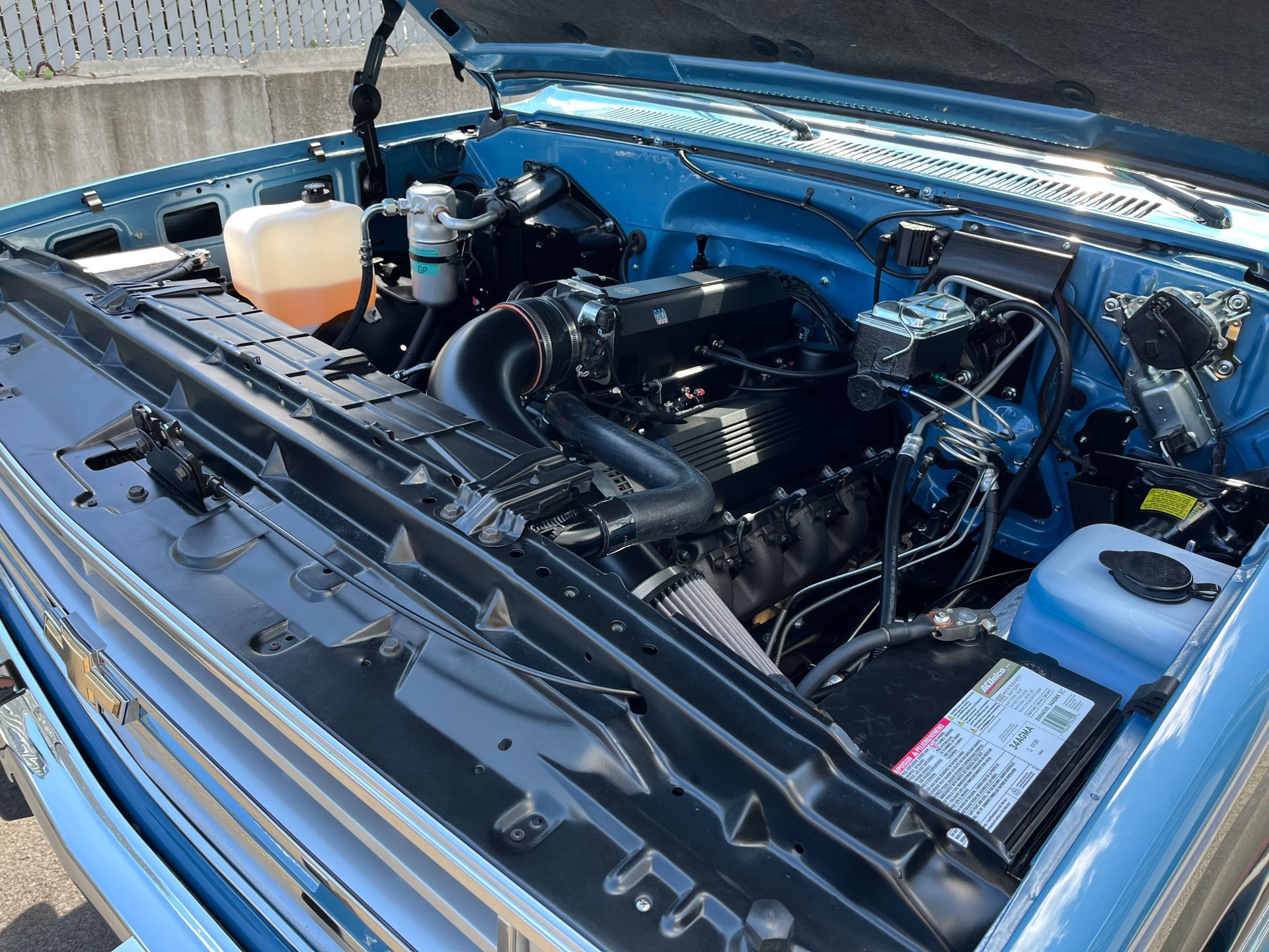 The engine of a blue truck is shown with the hood open