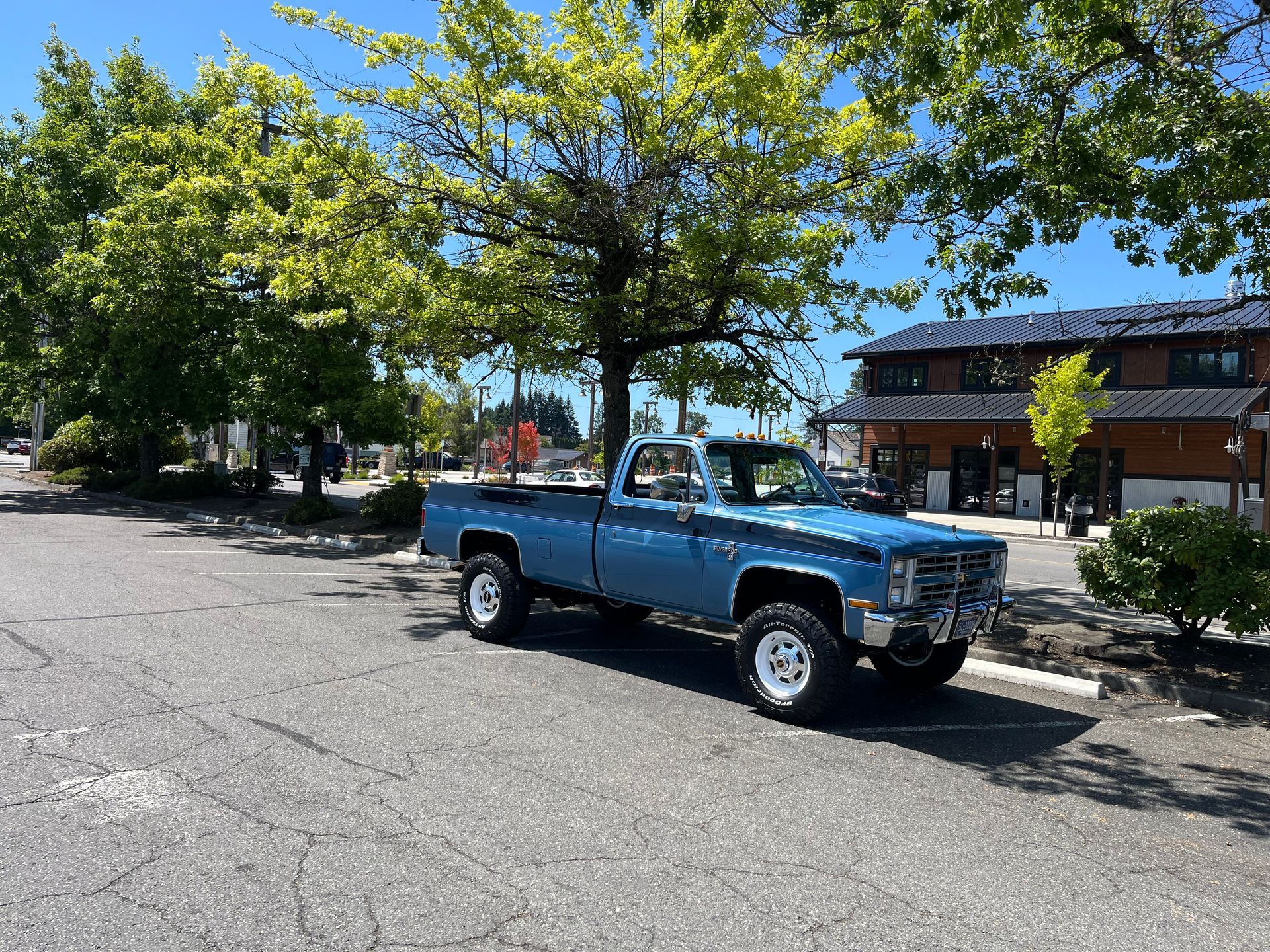 A blue truck is parked in a parking lot in front of a building.