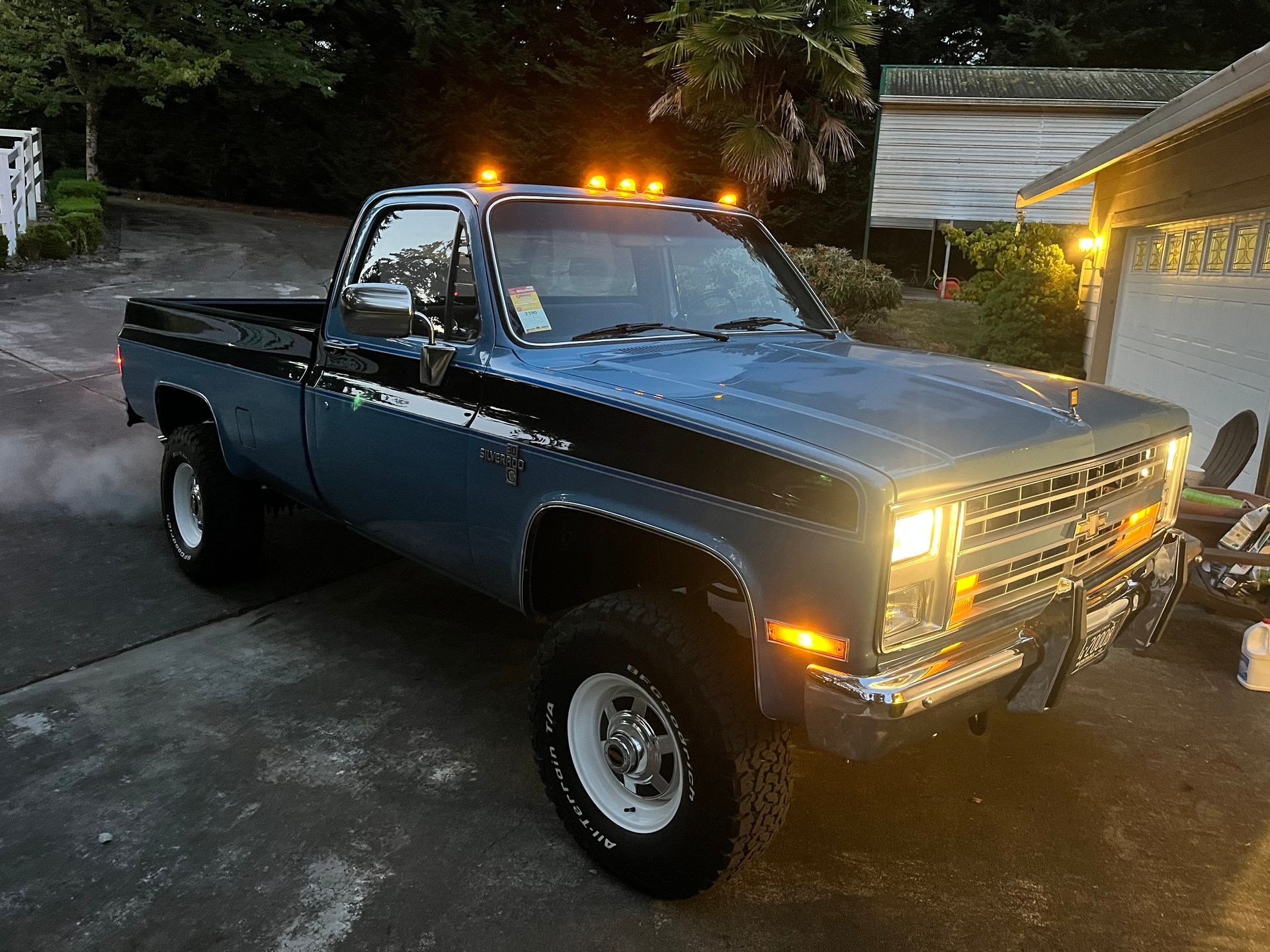 A blue truck is parked in a driveway next to a garage.