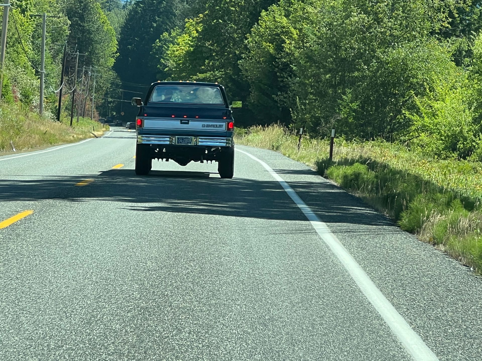 A truck is driving down a road with trees in the background
