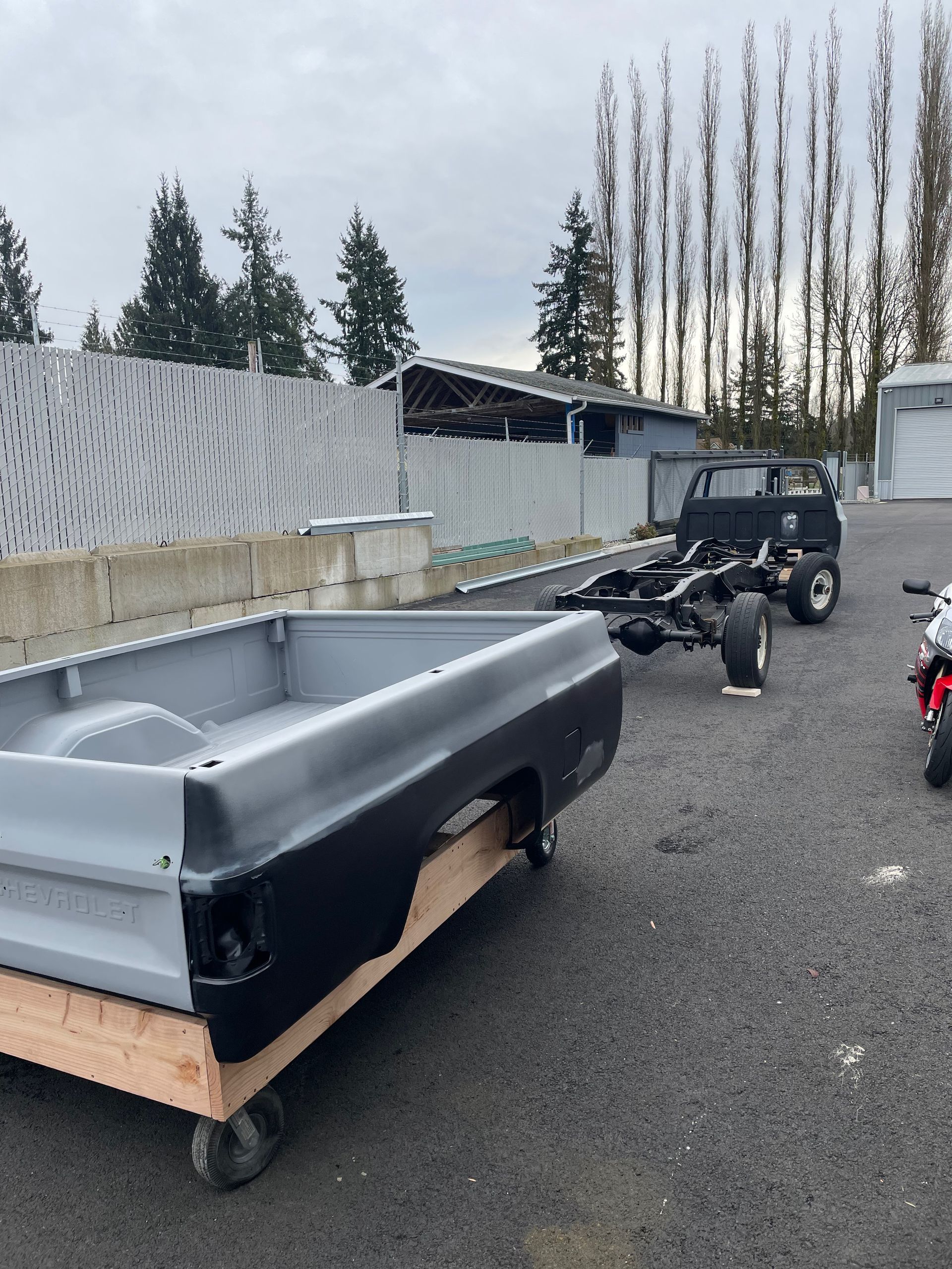 A truck bed is sitting on a wooden cart next to a motorcycle