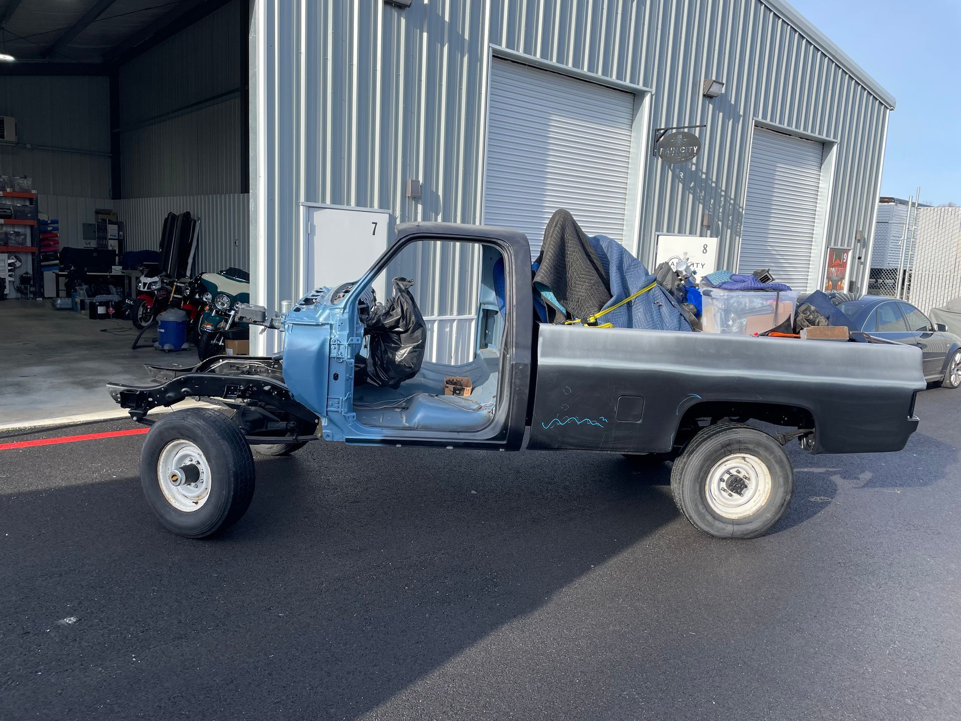 A blue truck is parked in front of a metal building.