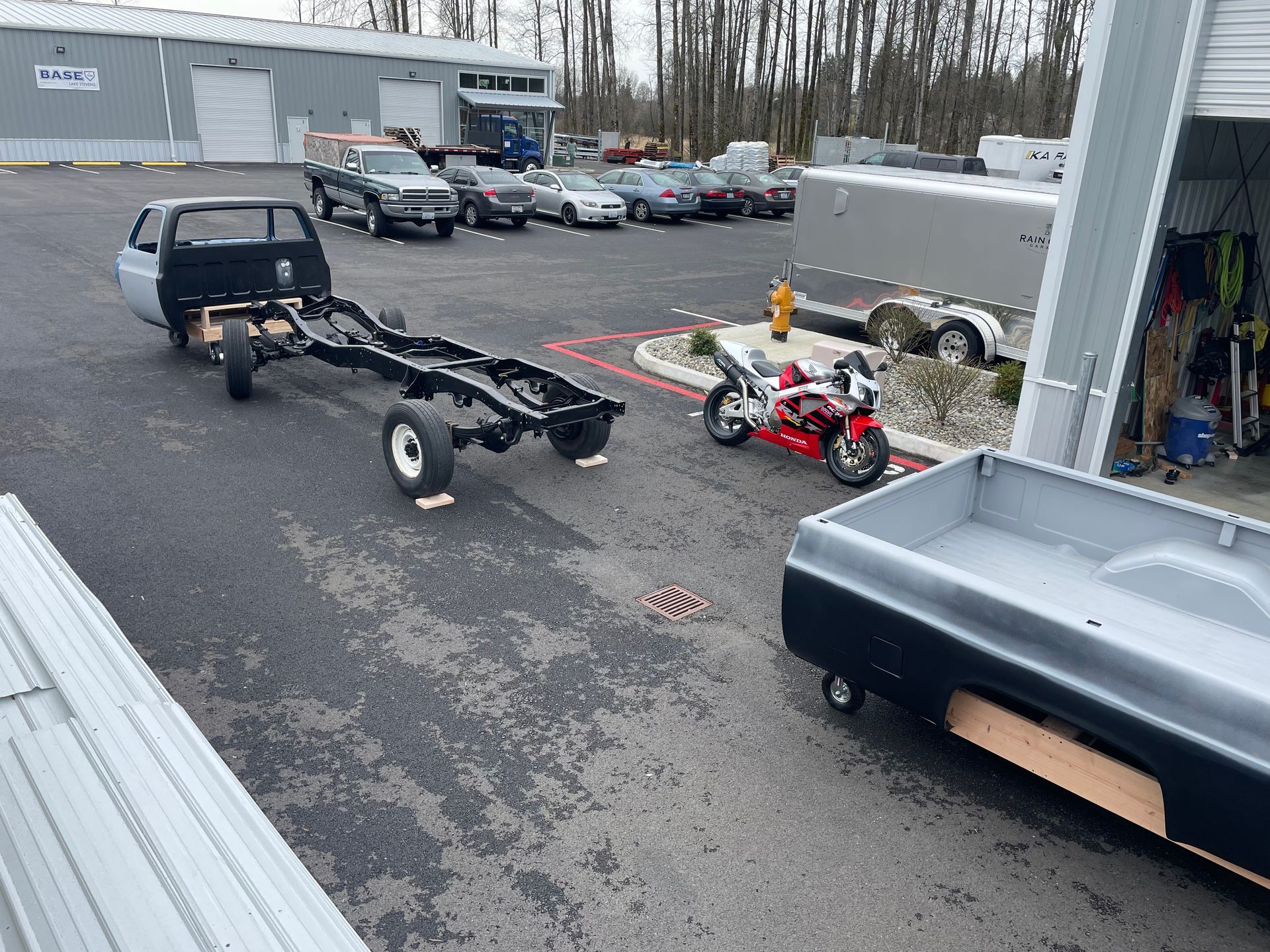 A motorcycle is parked next to a truck and trailer in a parking lot.
