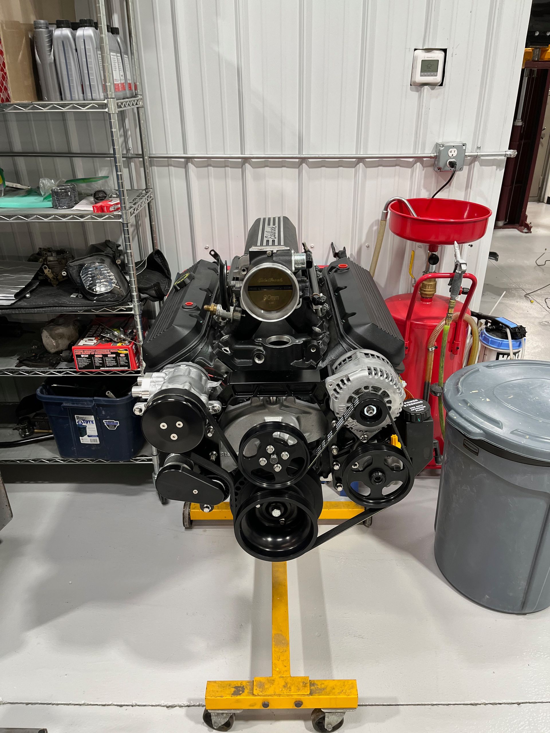 A v8 engine is sitting on a yellow stand in a garage.