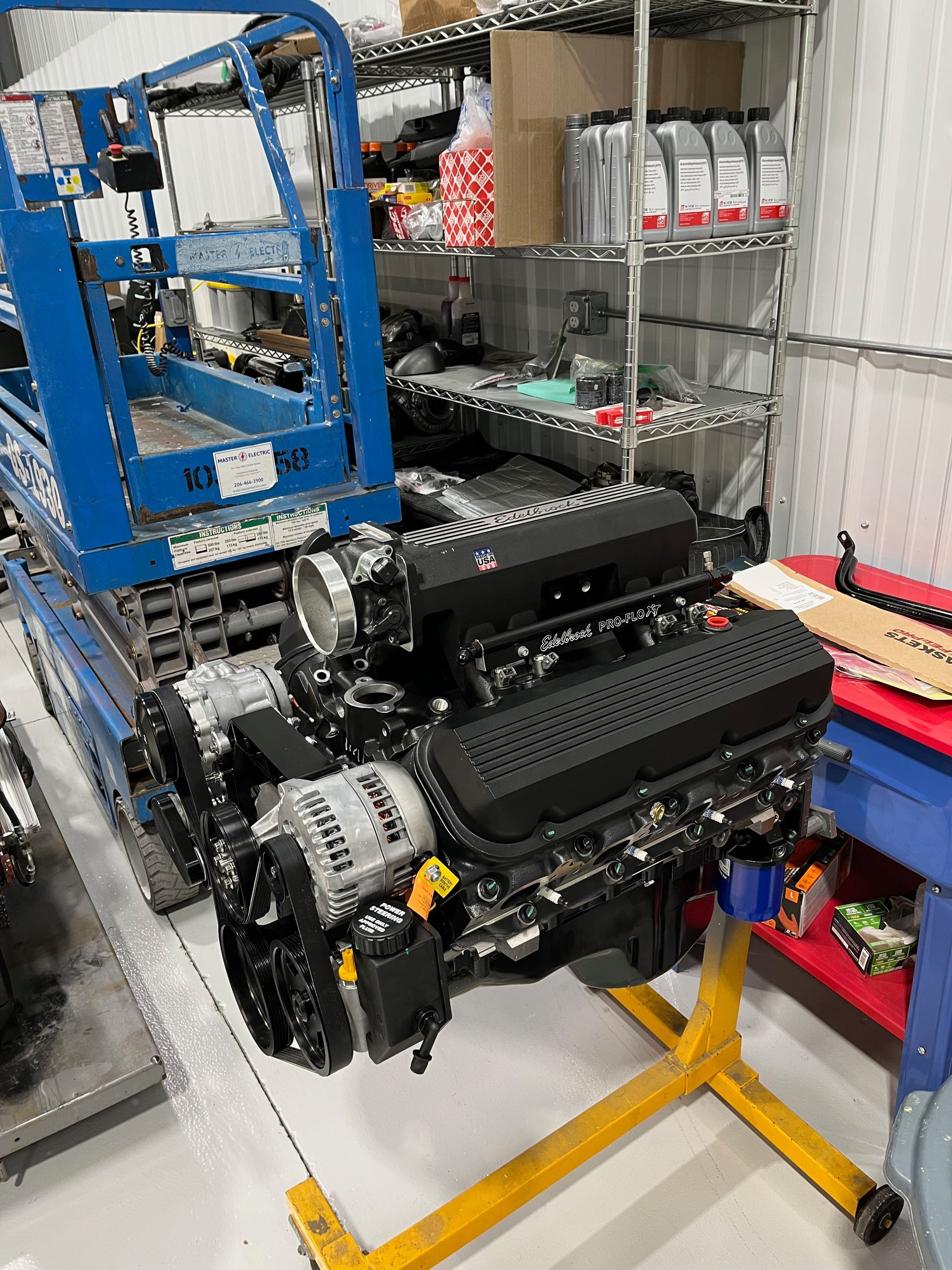 A large engine is sitting on top of a yellow stand in a garage.