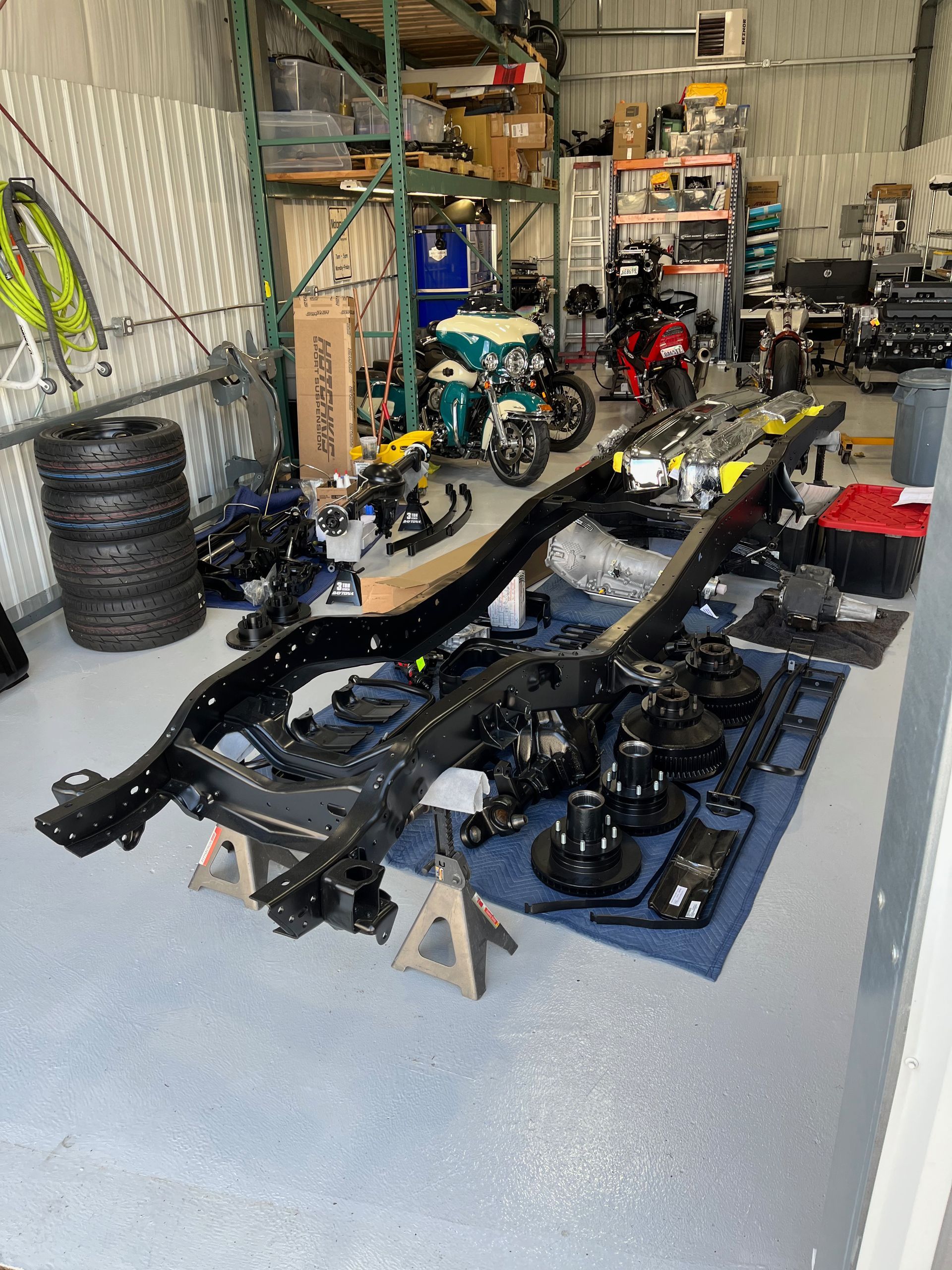A car chassis is sitting on a table in a garage.