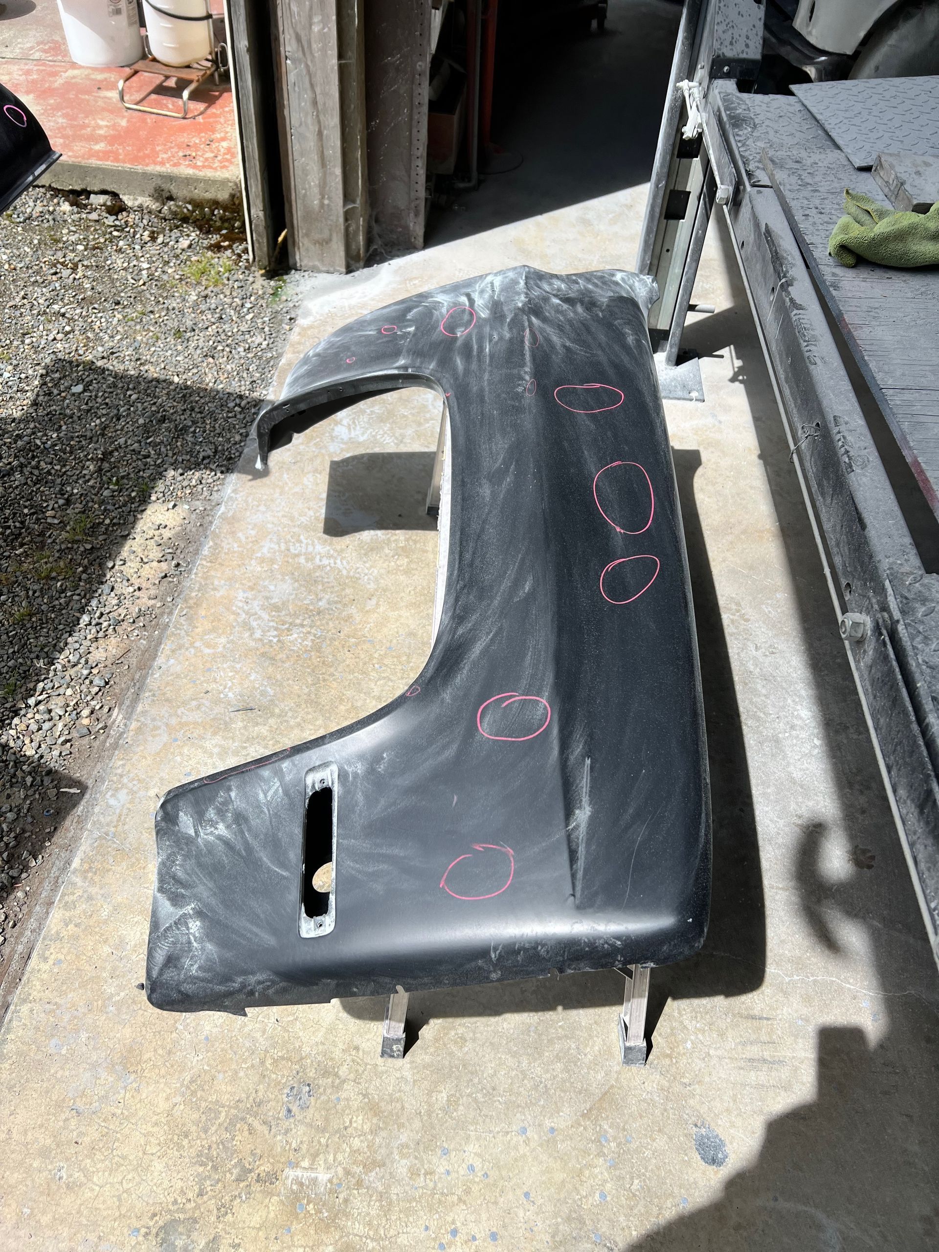 A fender is sitting on the ground next to a boat.