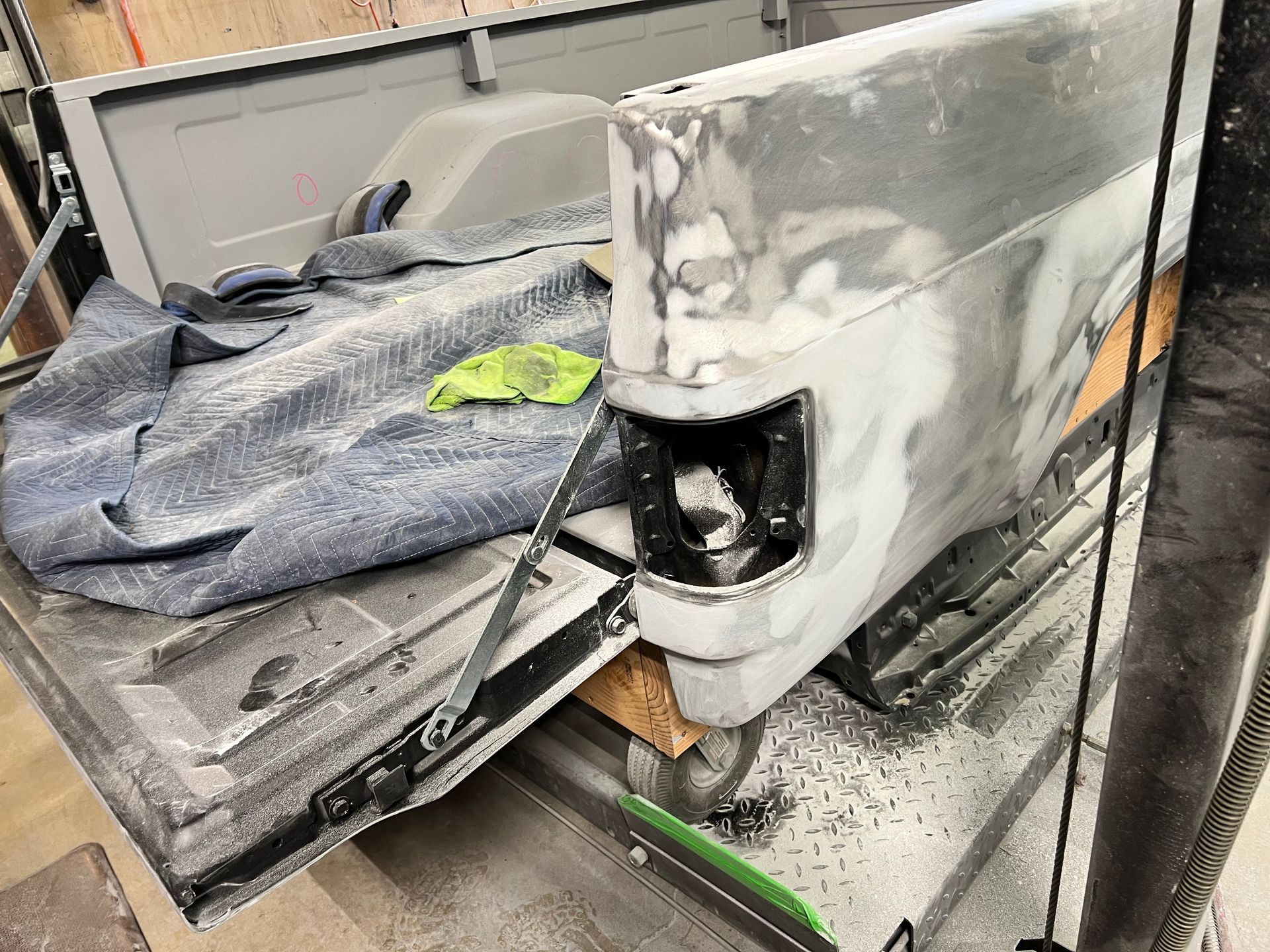 A truck bed is being painted in a garage.