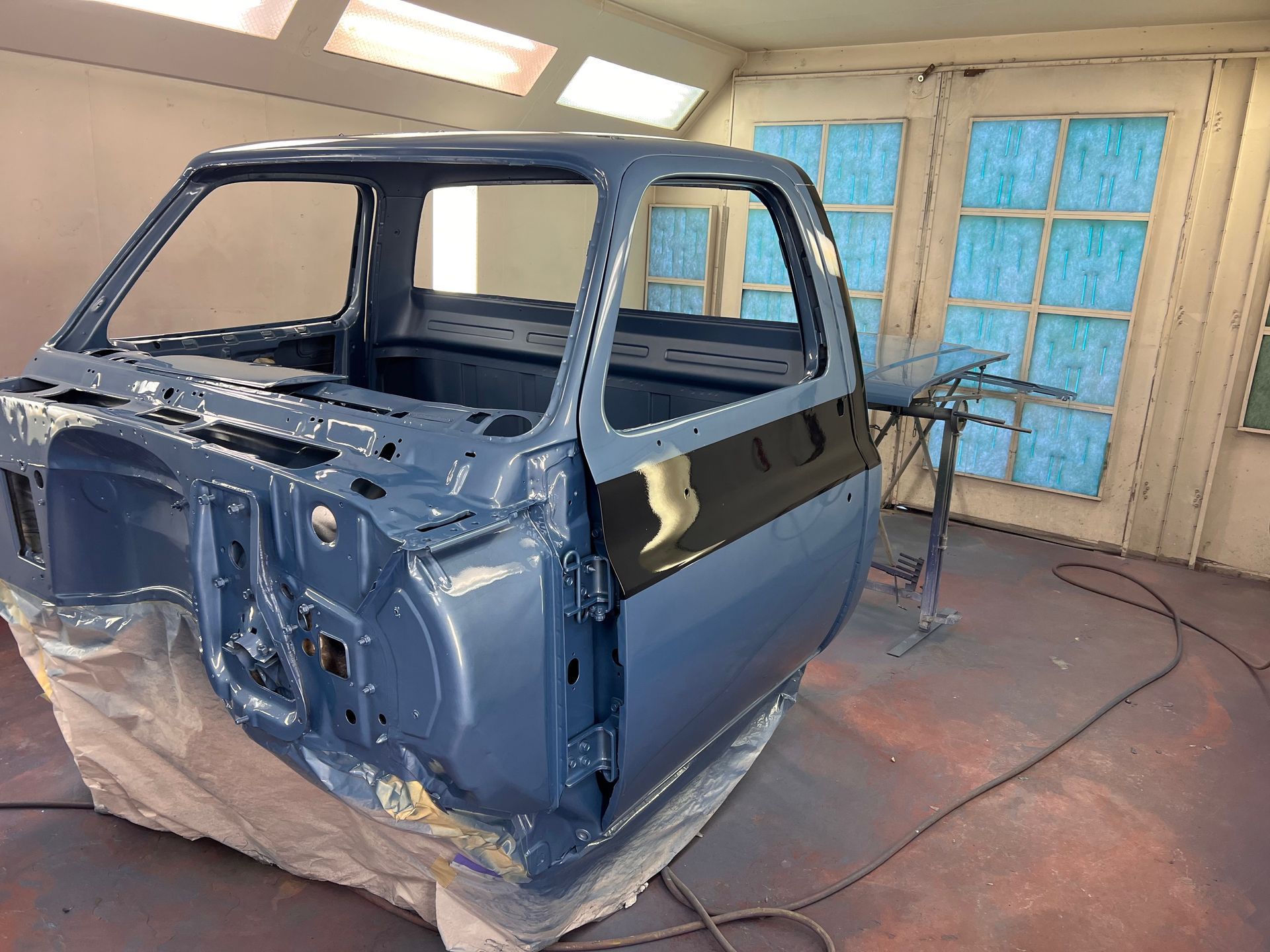 A blue truck is being painted in a paint booth.