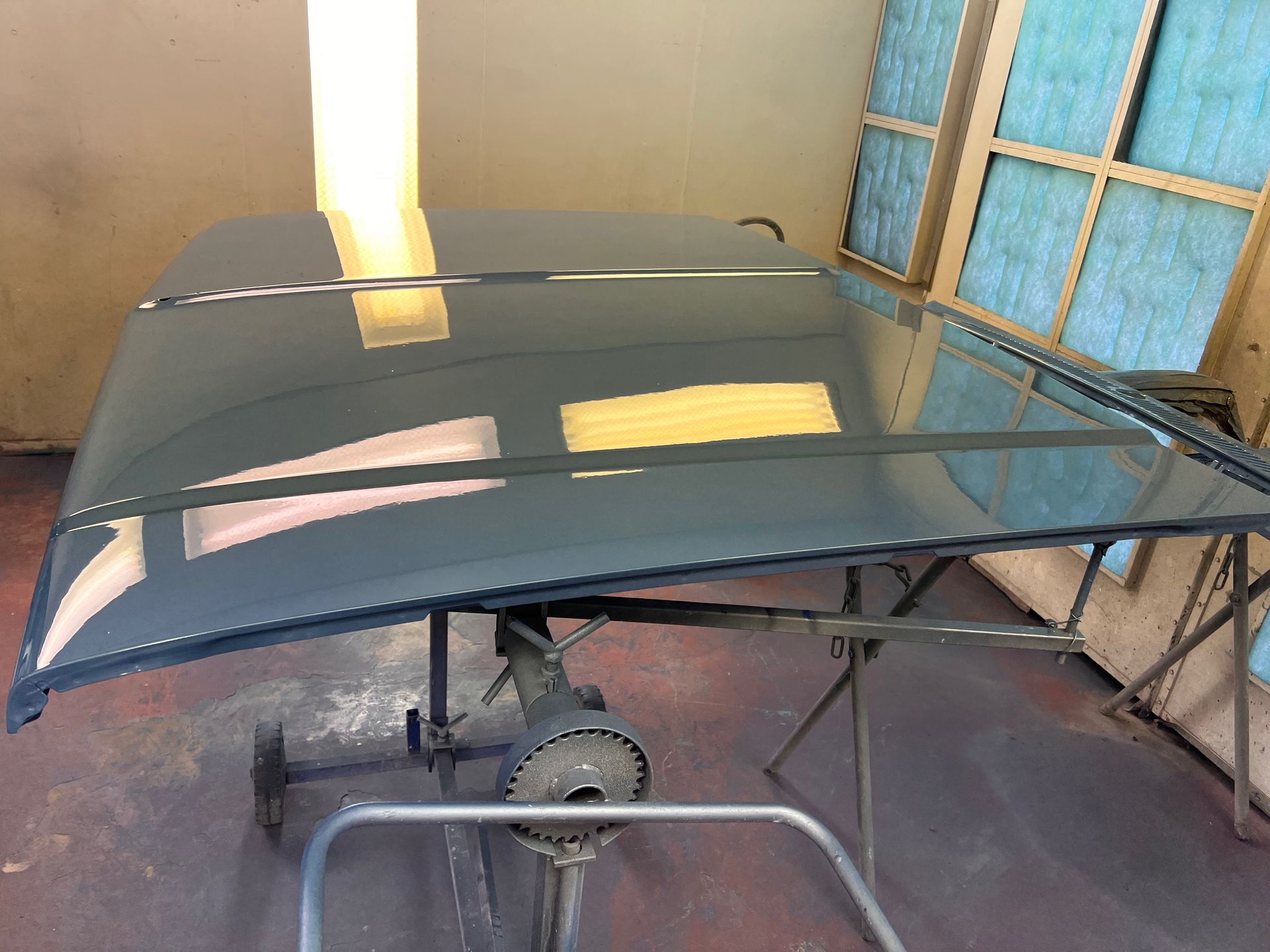 A car hood is sitting on a stand in a garage