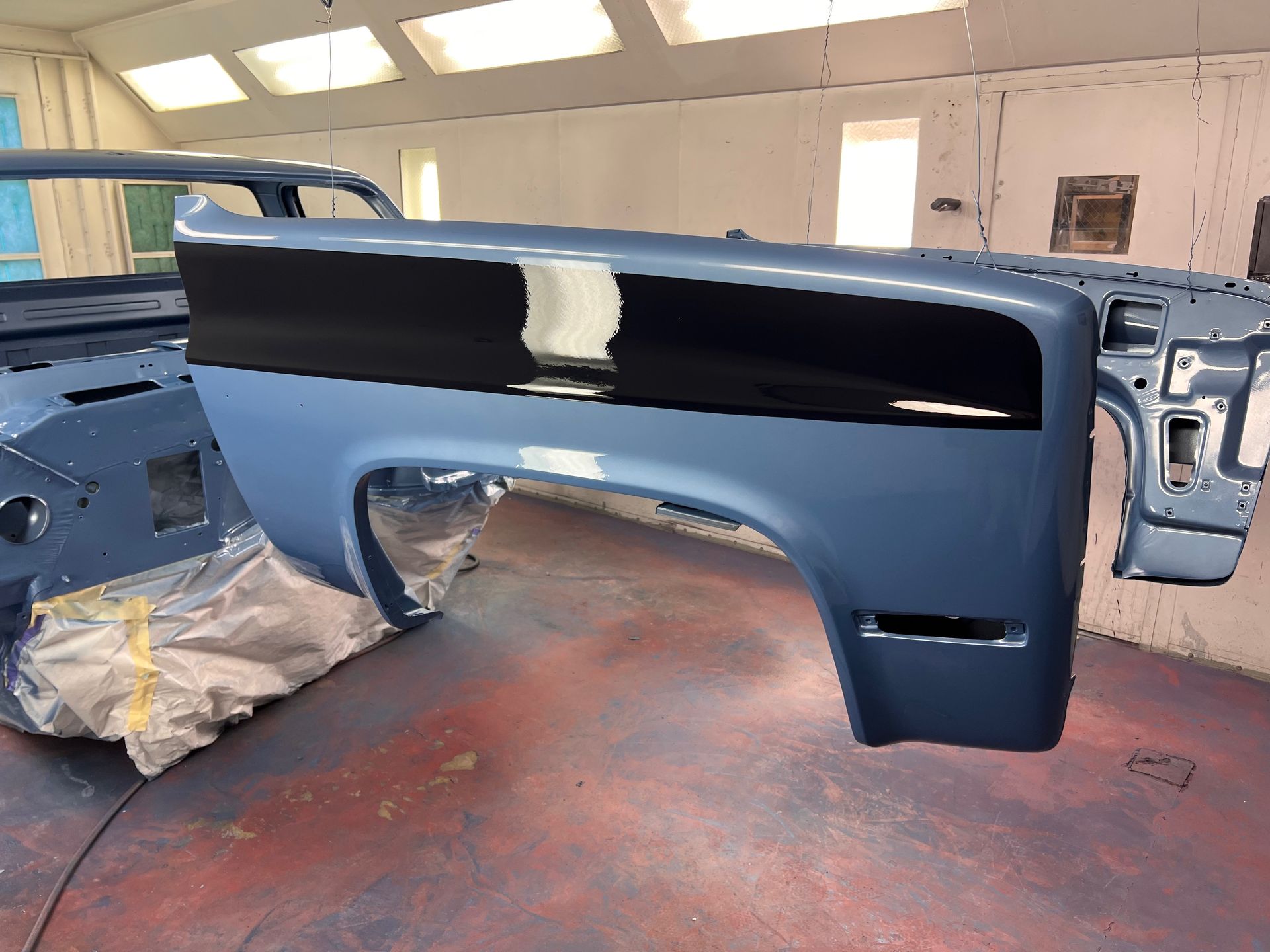 A blue car is being painted in a garage