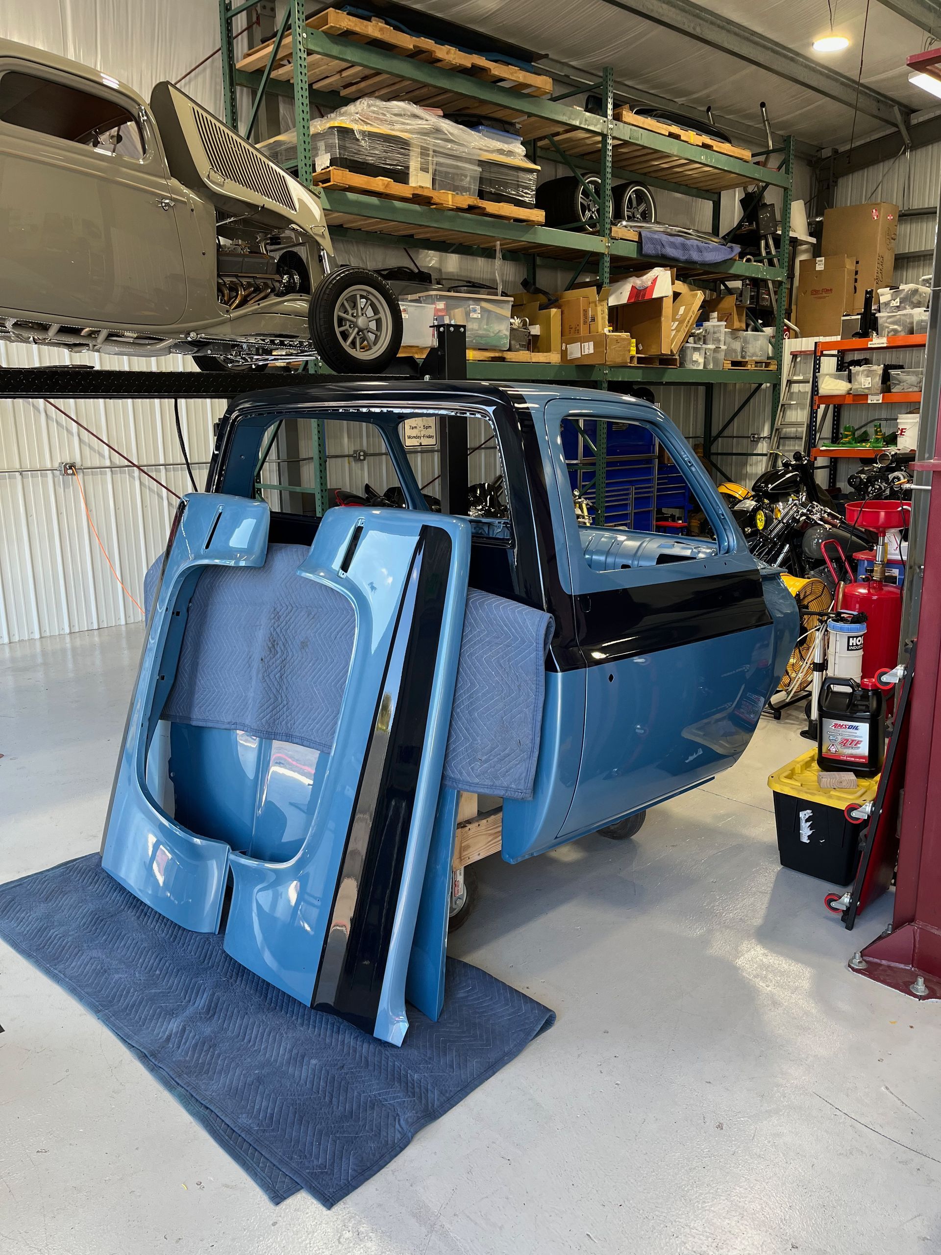 A blue car is sitting on top of a blue mat in a garage.