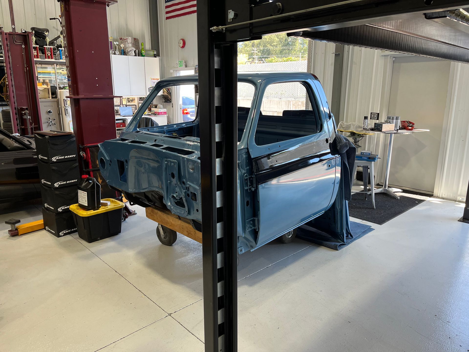 A blue truck is sitting on a lift in a garage.