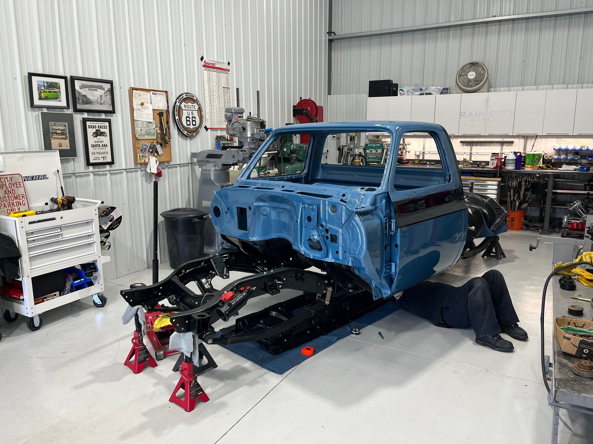 A man is working on a blue truck in a garage.