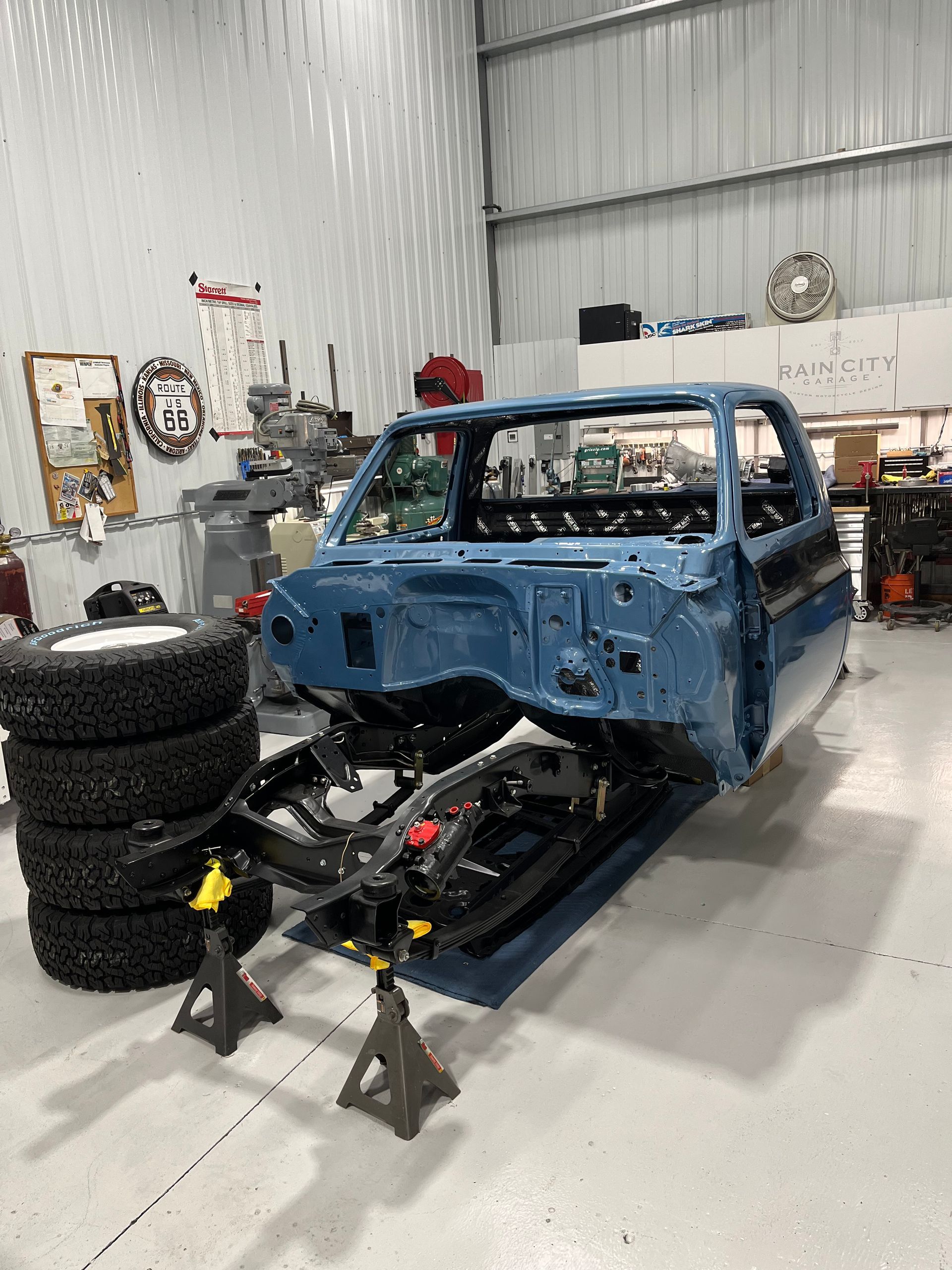 A blue truck is being built in a garage.