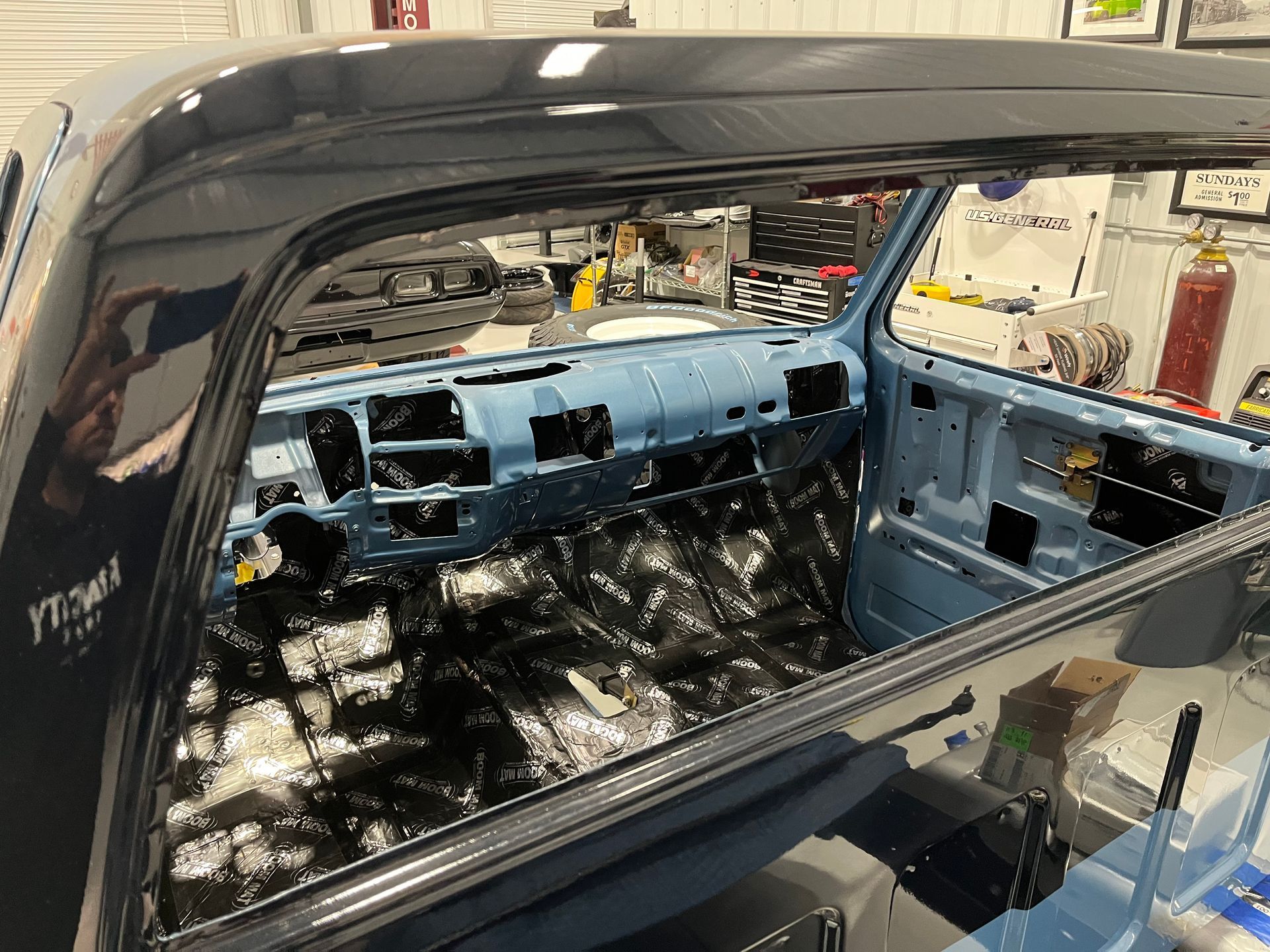 A blue truck is being built in a garage.