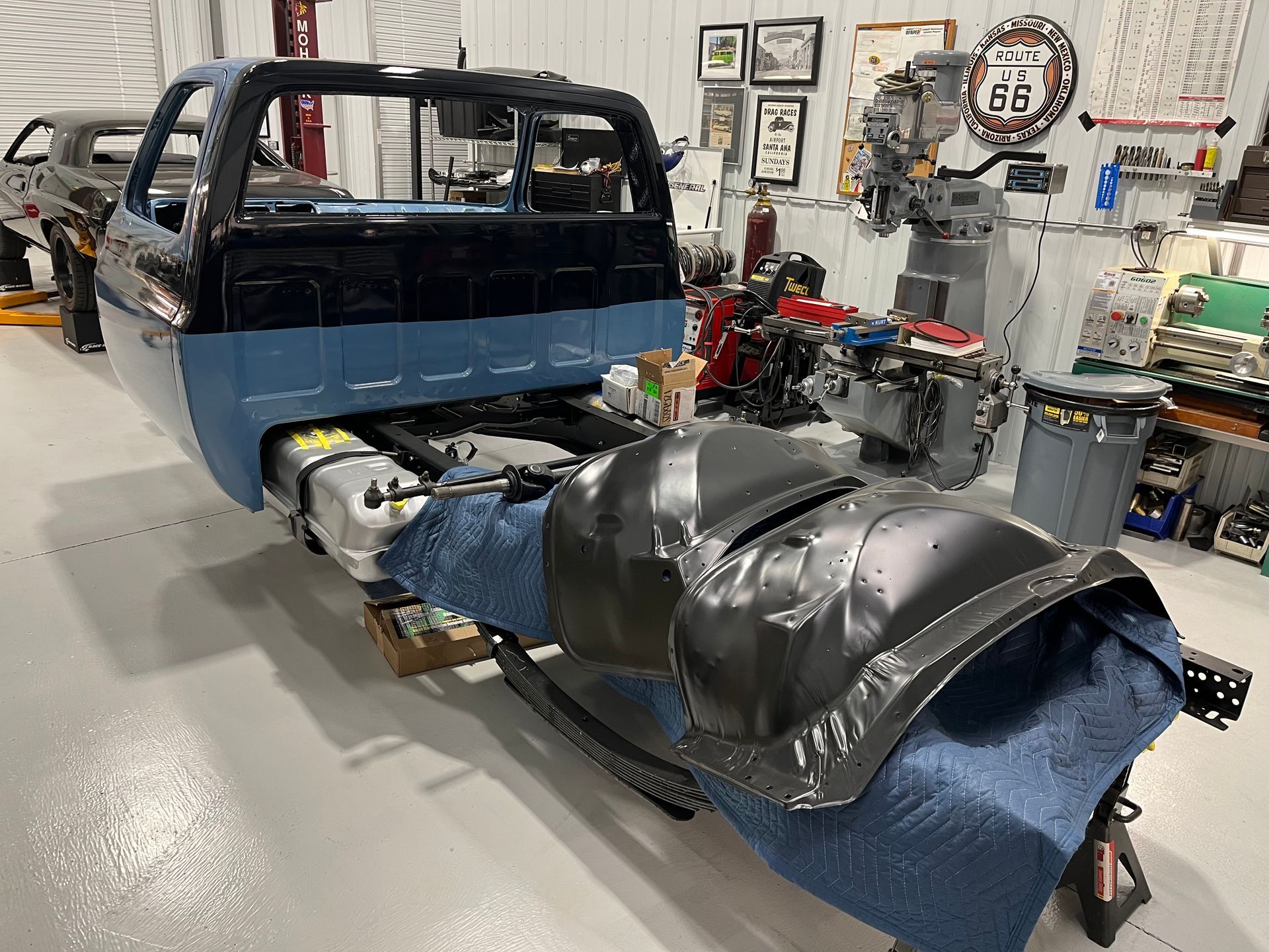 A blue truck is being built in a garage.