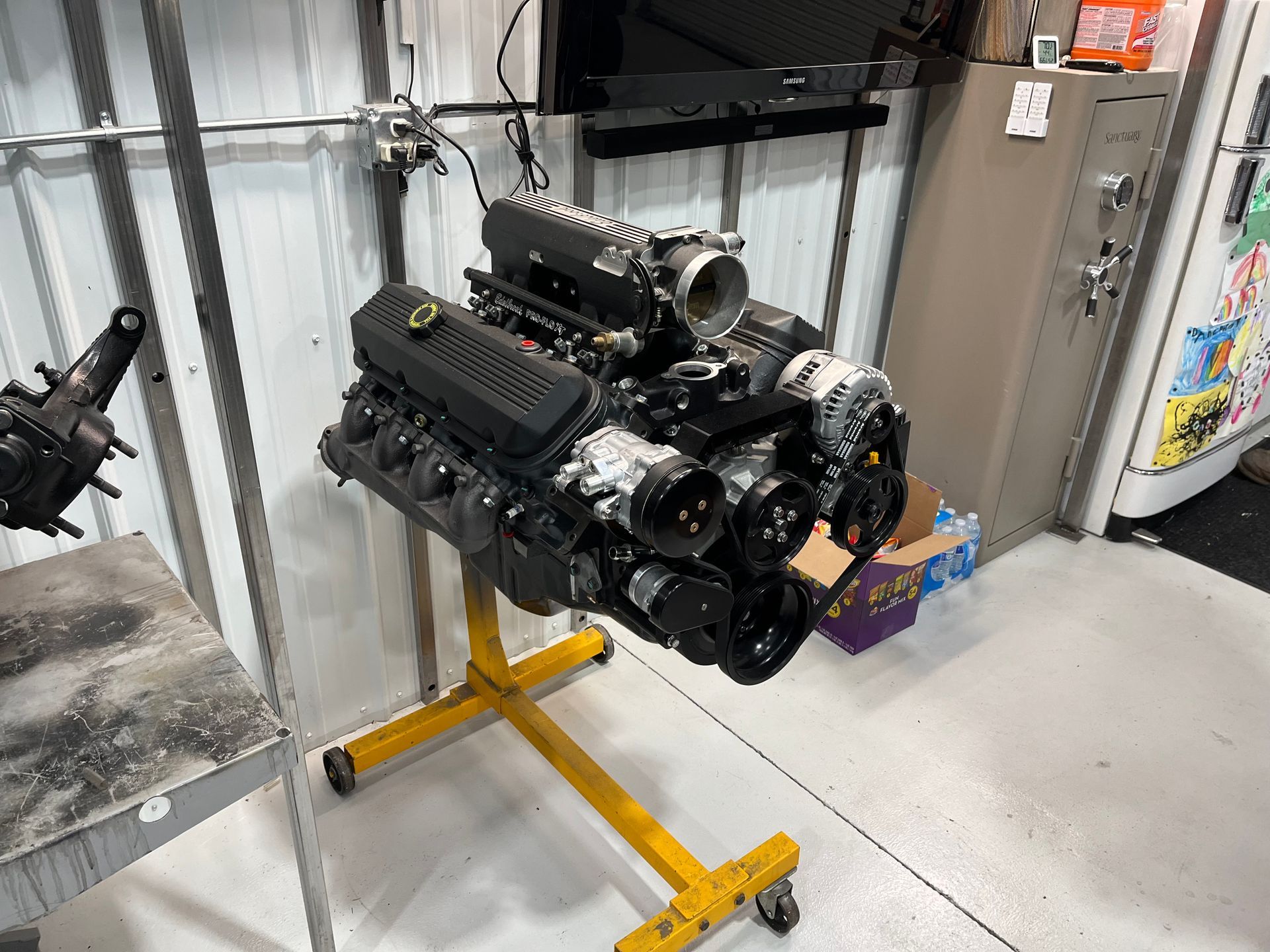 A black engine is sitting on a yellow stand in a garage.