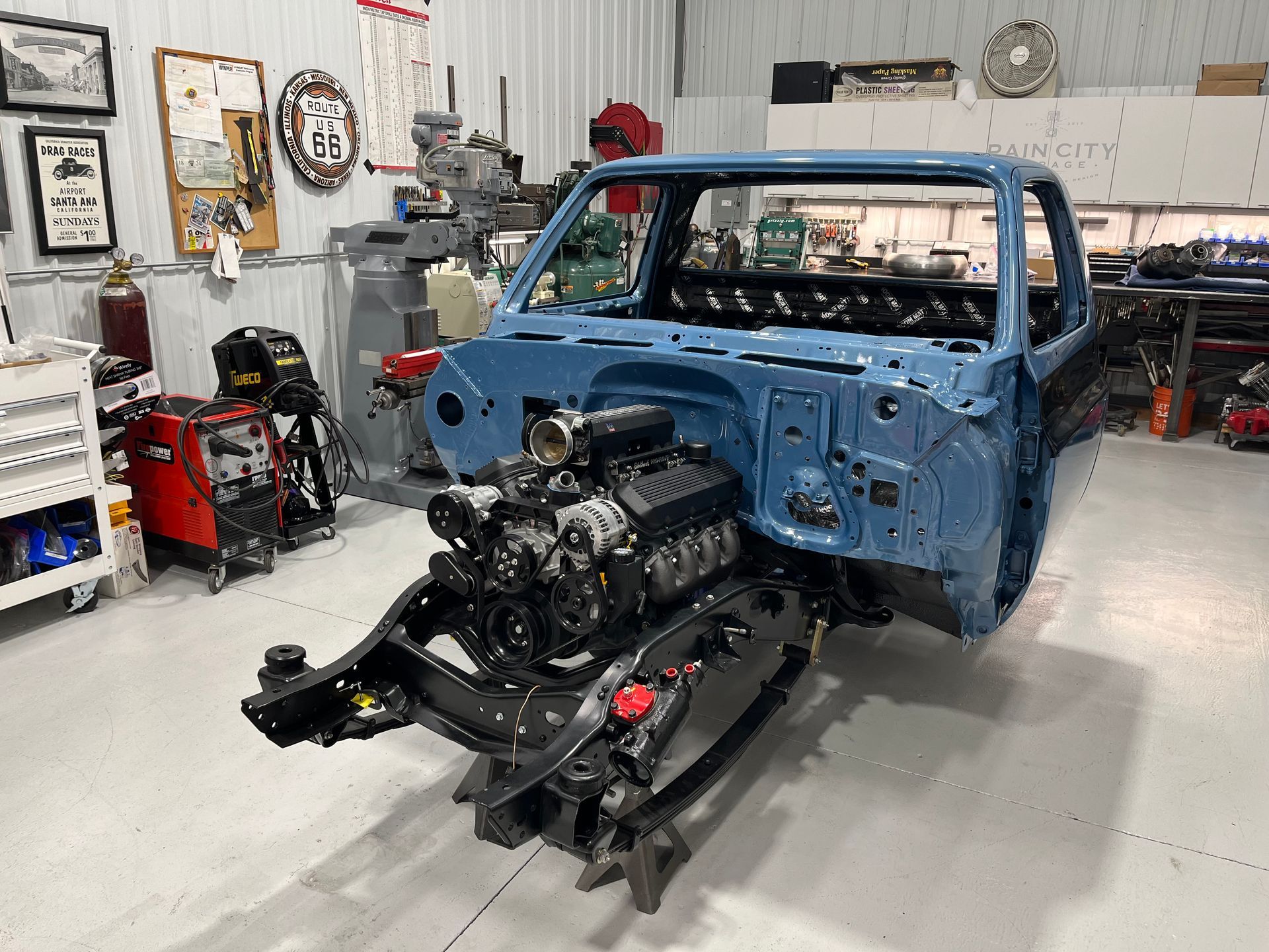 A blue truck is being built in a garage.