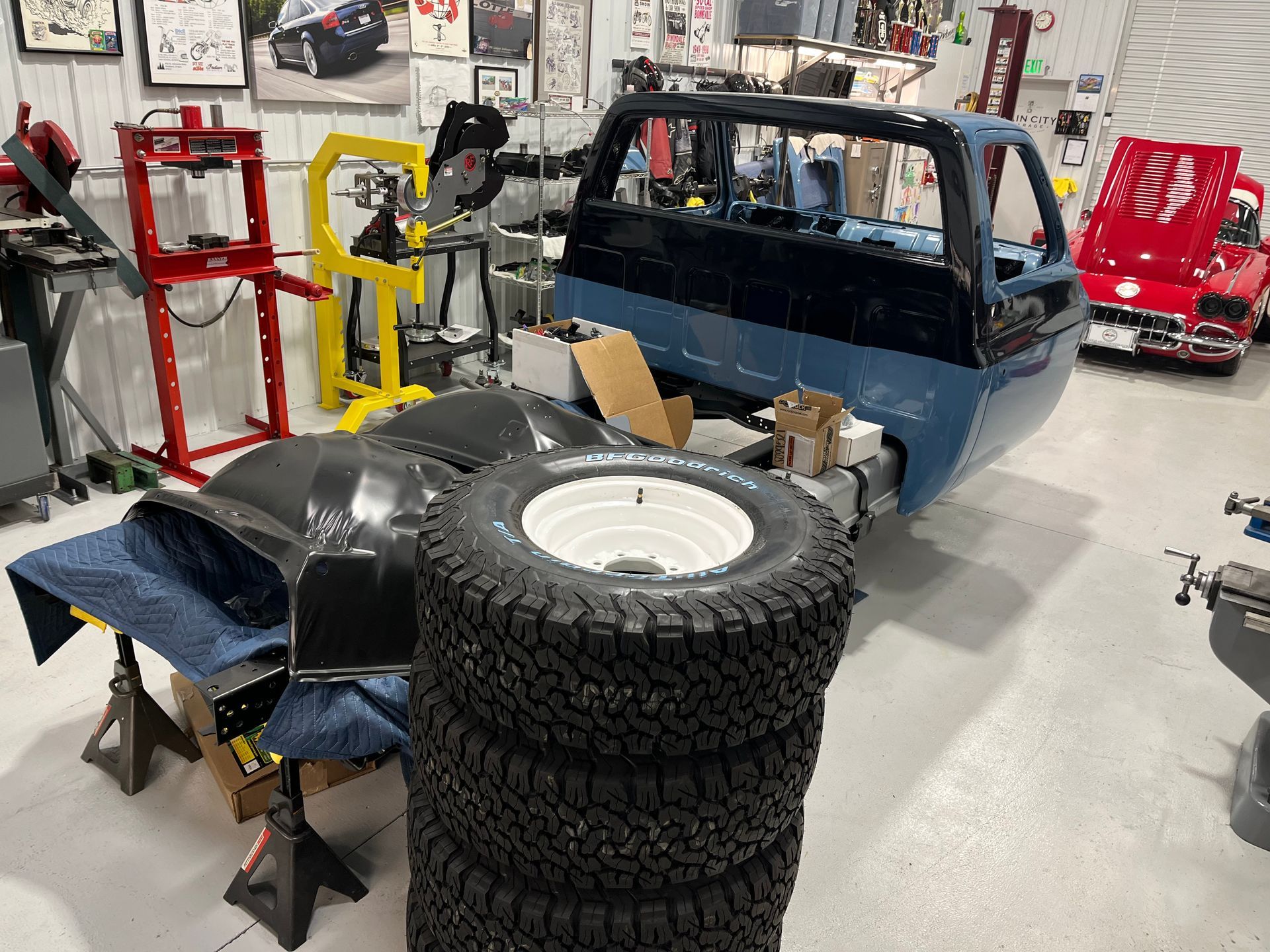 A stack of tires is sitting in front of a truck in a garage.