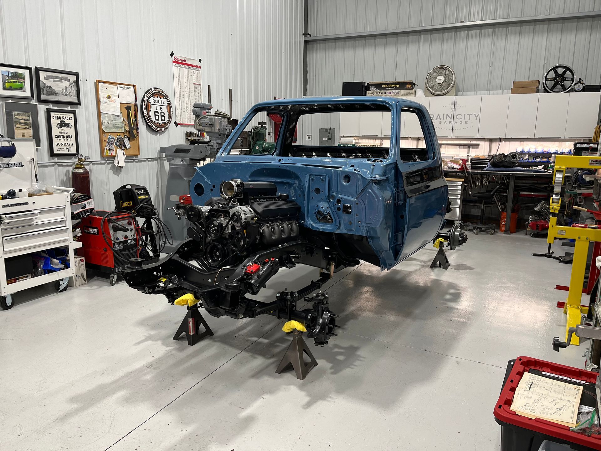 A blue truck is being built in a garage.