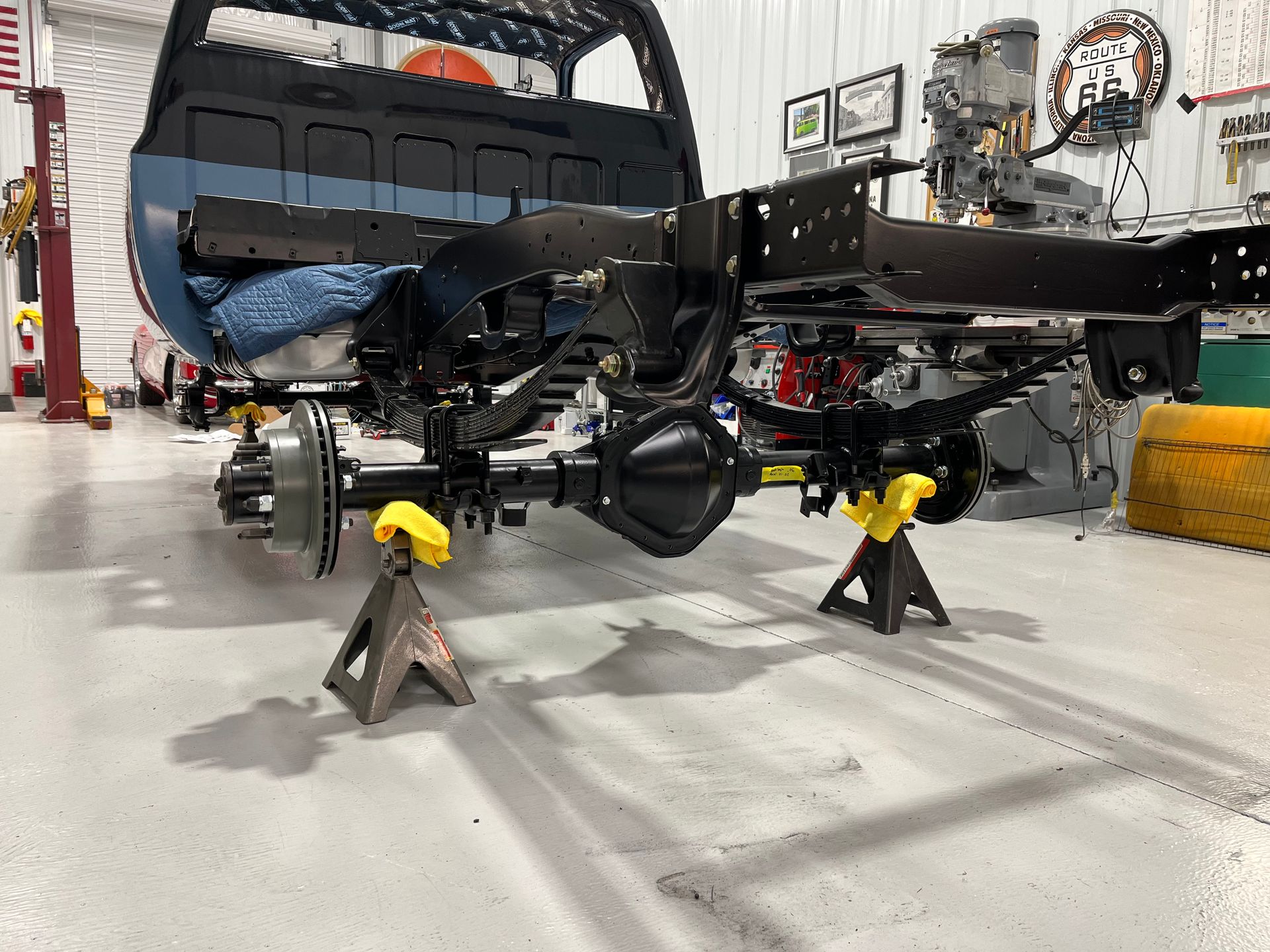 A truck is being built in a garage and is sitting on jack stands.