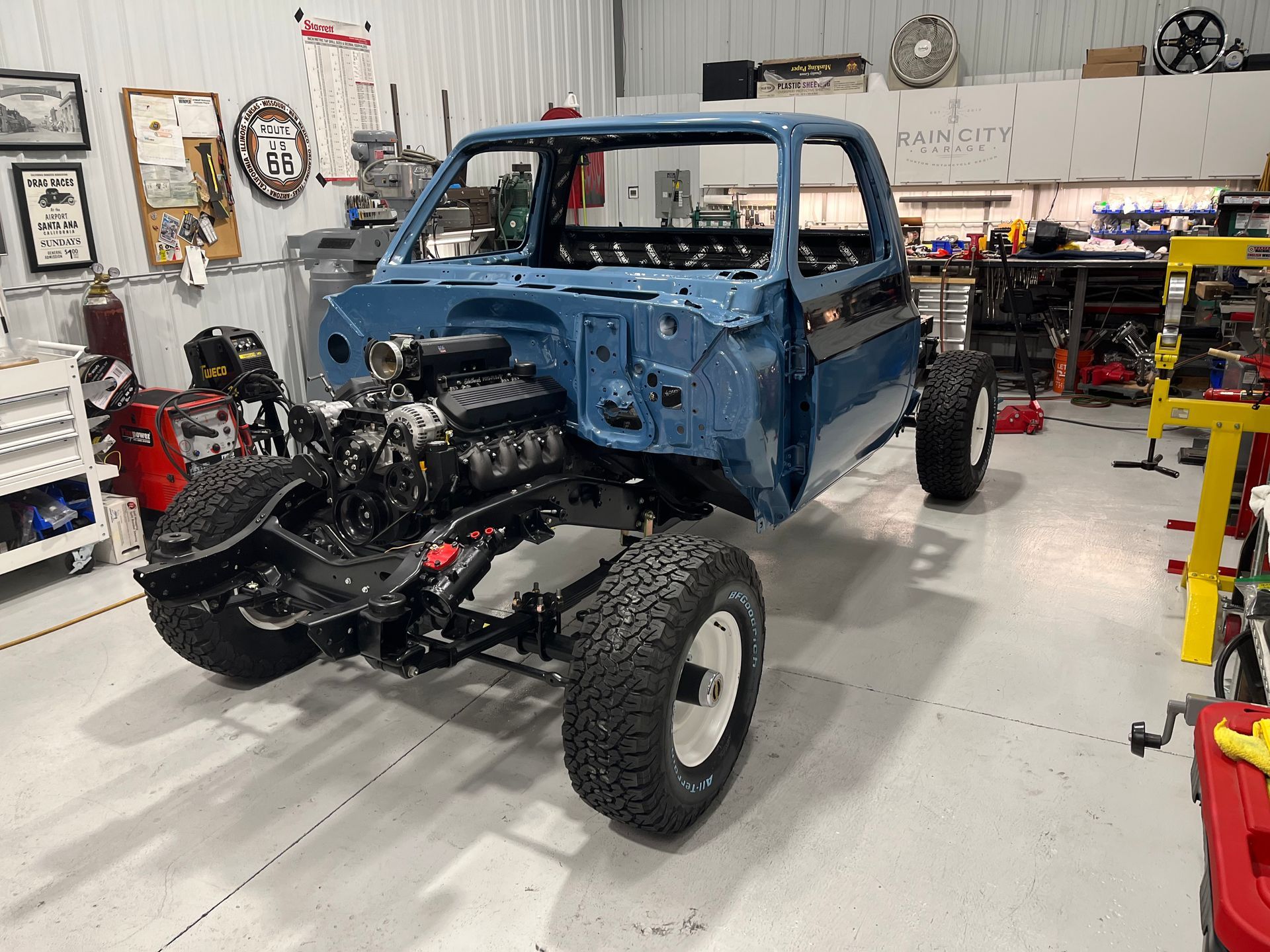 A blue truck is being built in a garage.