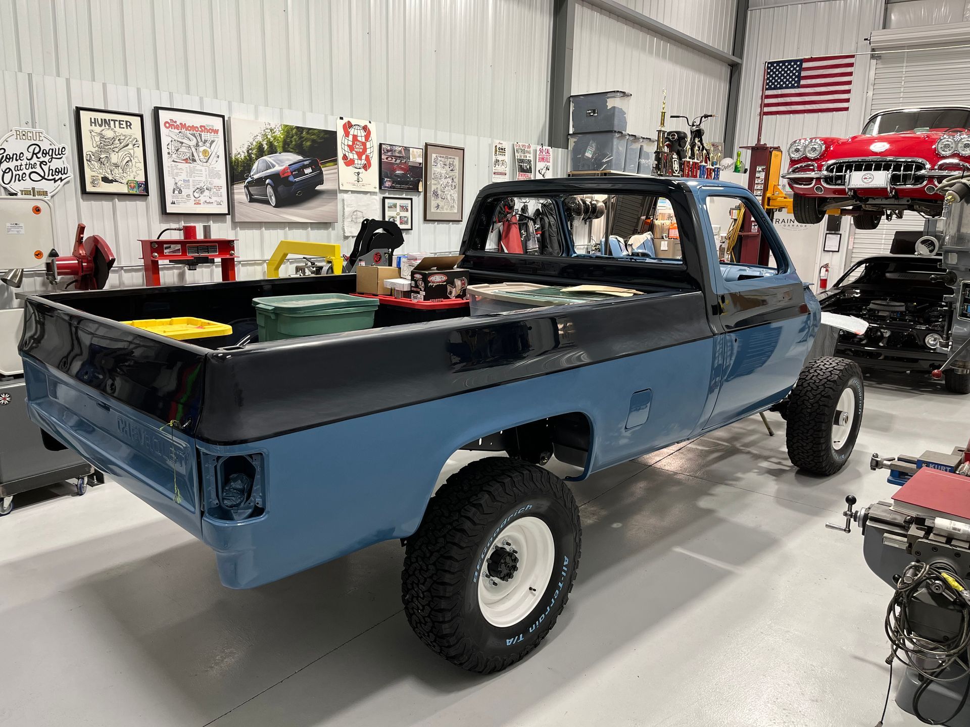 A blue truck is parked in a garage next to a red car.