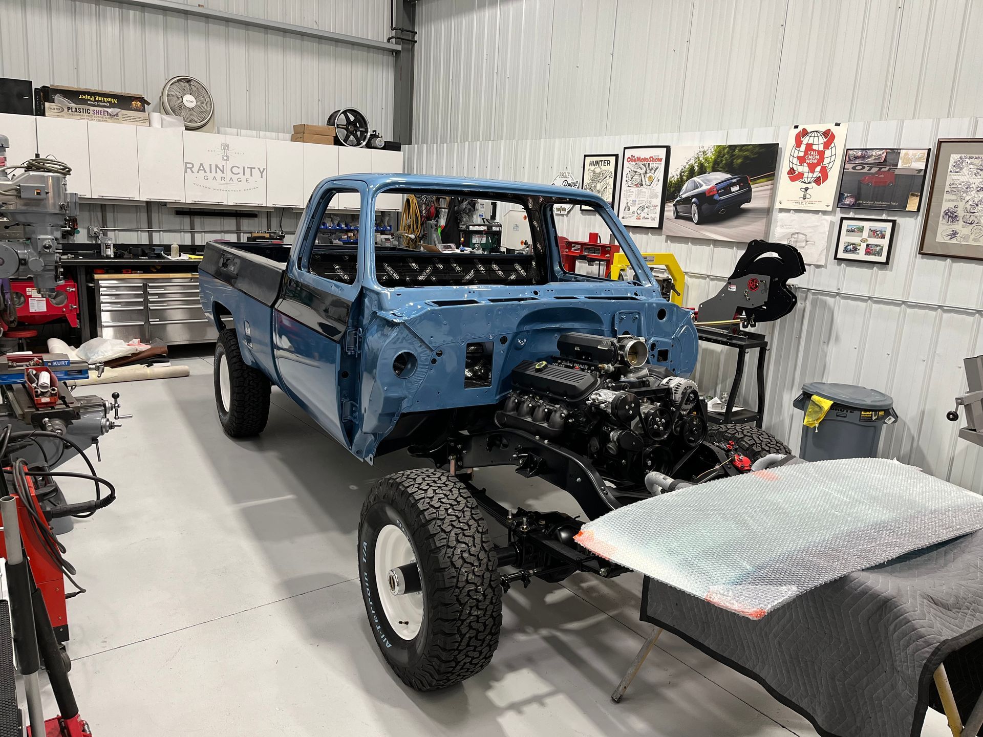 A blue truck is being built in a garage.