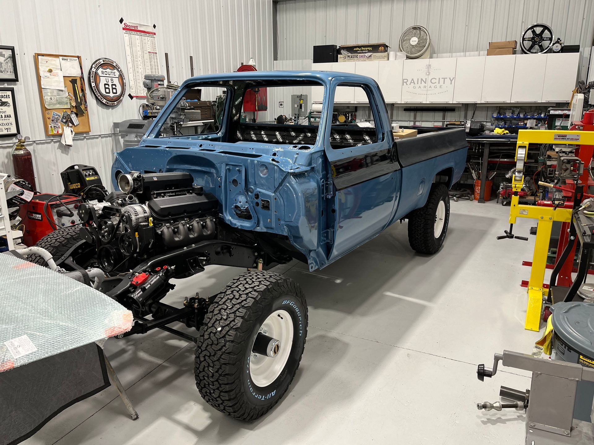 A blue truck is being built in a garage.