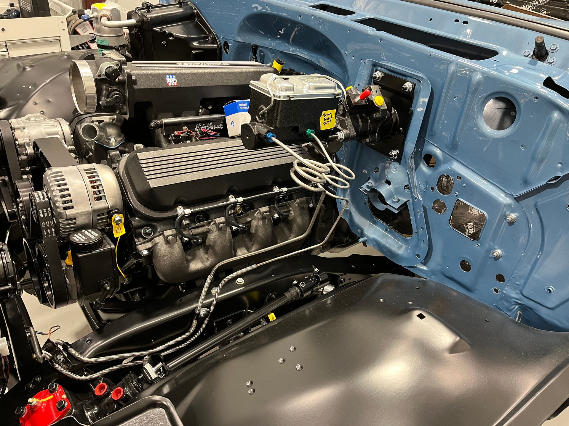 A blue car with a black engine is being built.