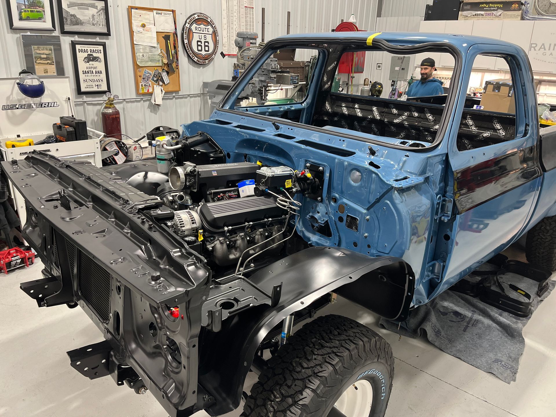 A blue truck is being built in a garage.
