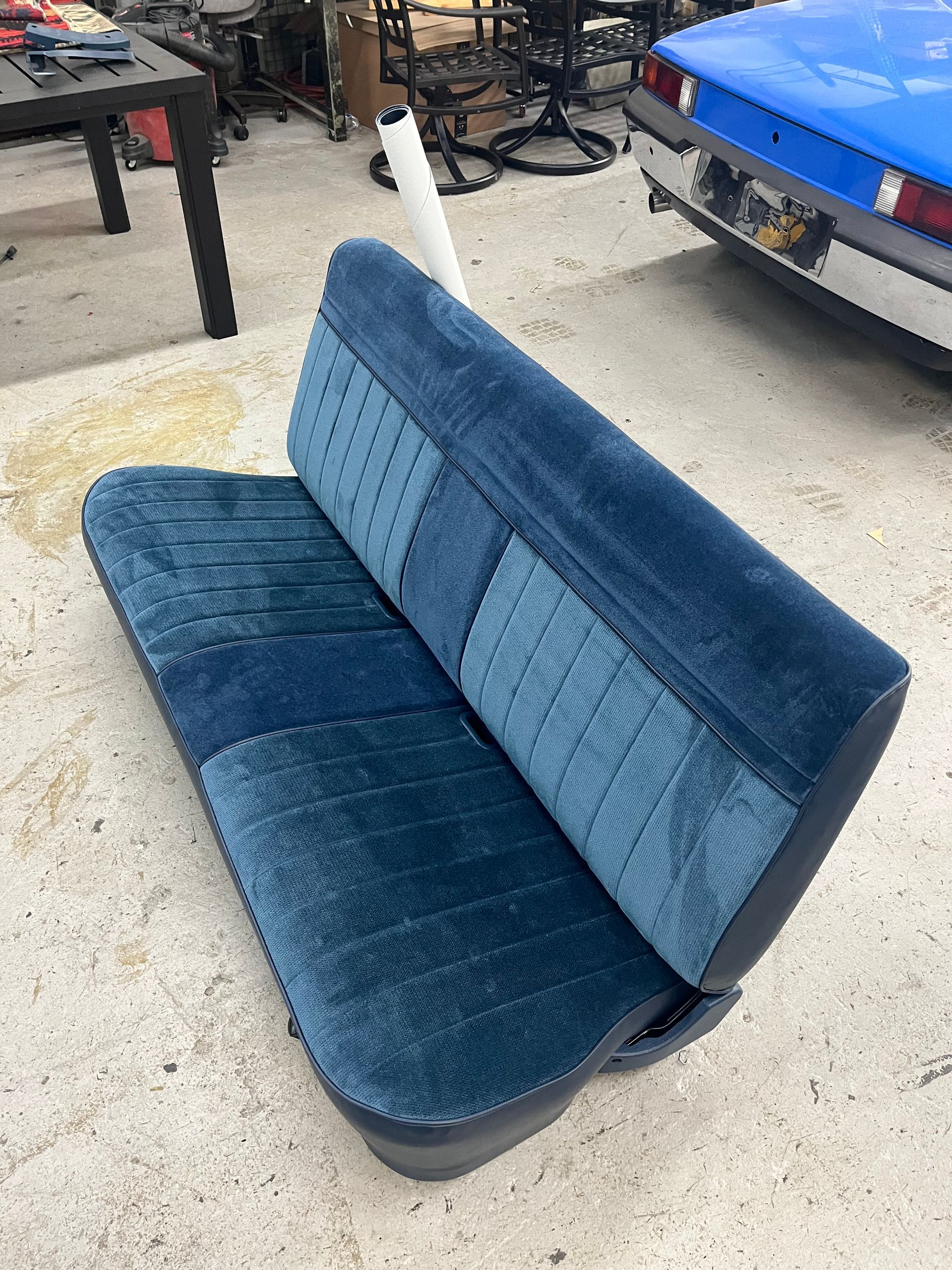 A blue couch is sitting on the ground next to a blue car.