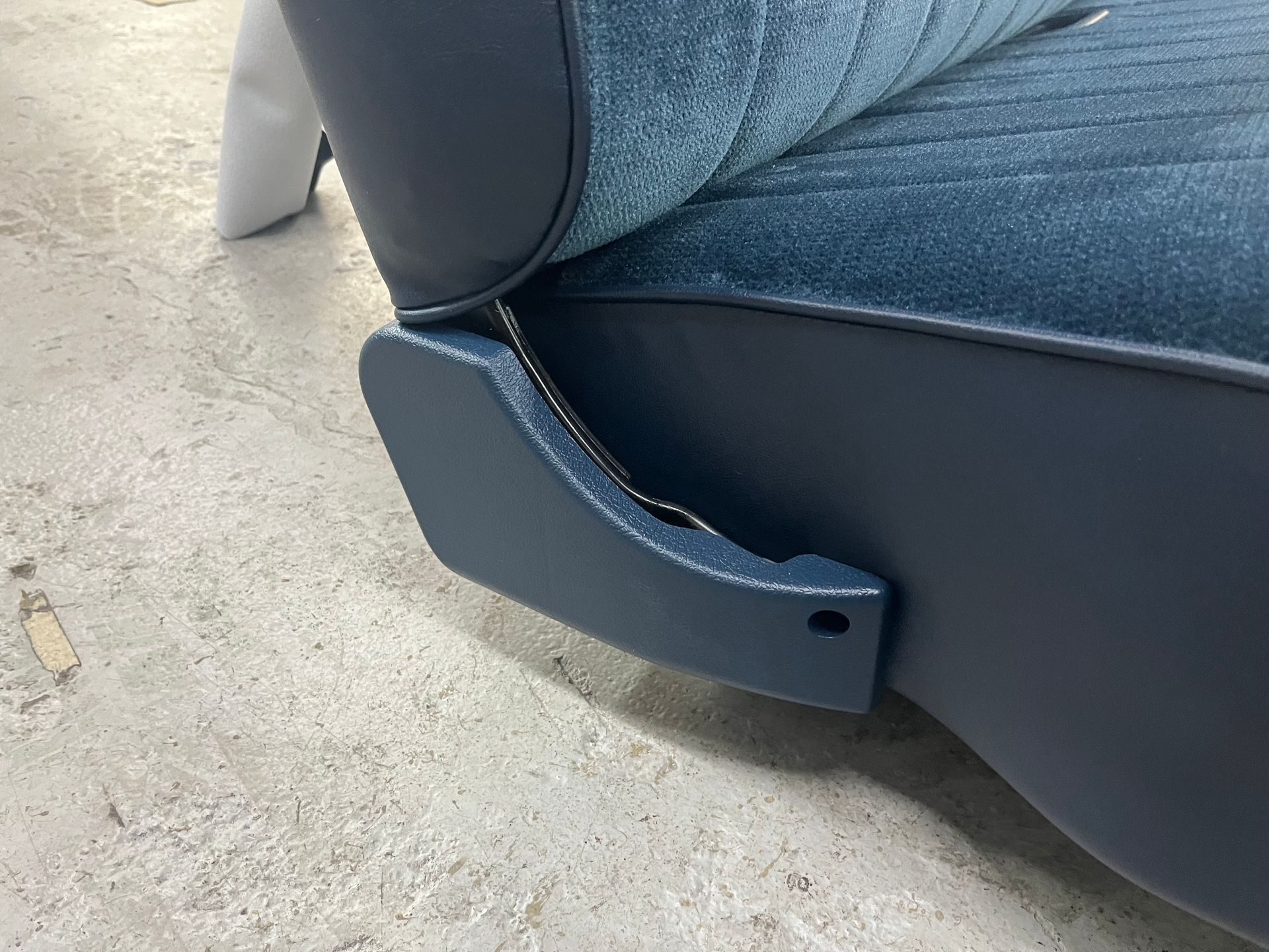 A blue chair is sitting on a concrete floor.
