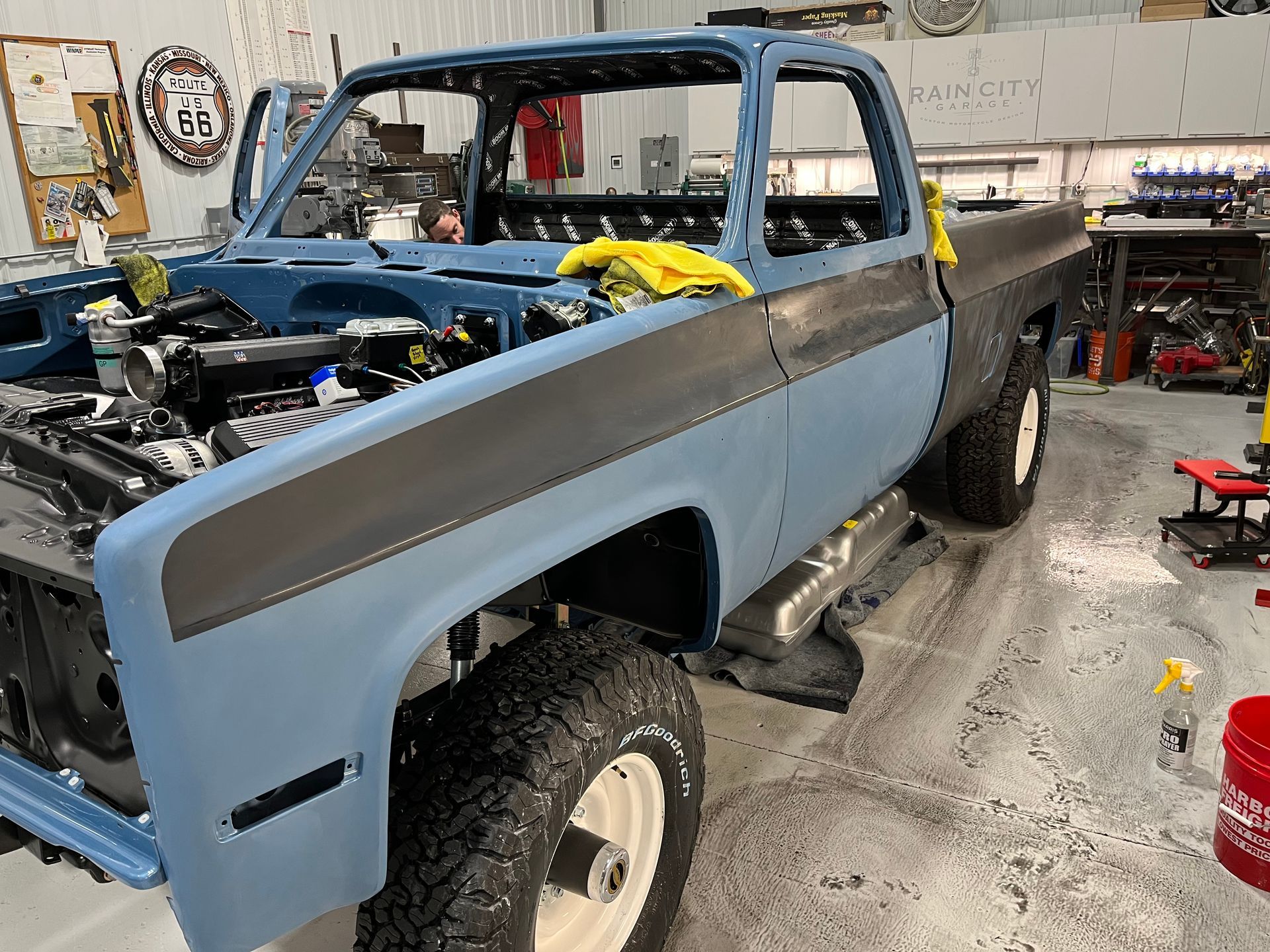 A blue truck is being built in a garage.