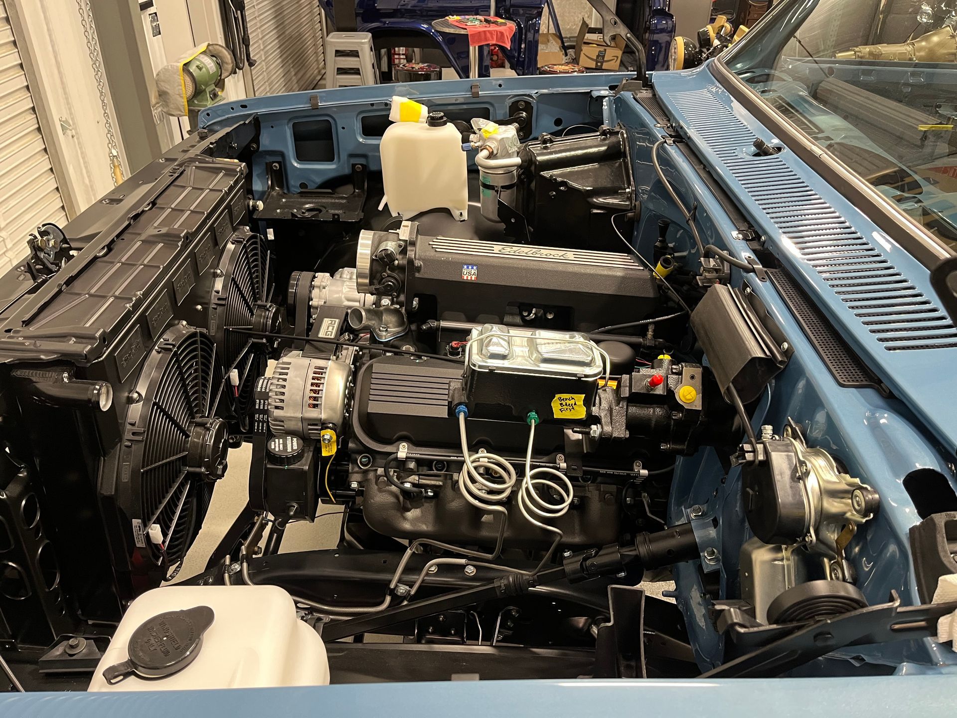 The engine of a blue car is shown with the hood open.