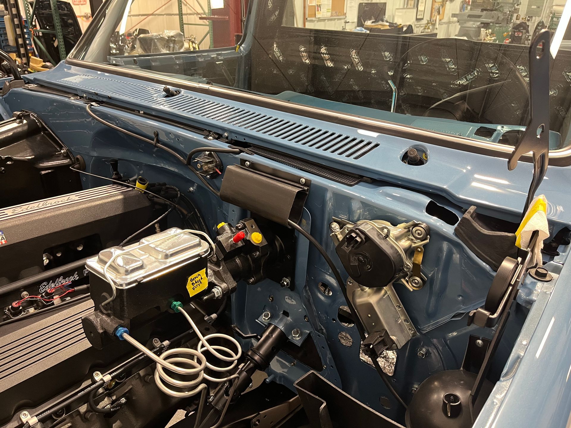 A blue car with the hood open and a lot of wires coming out of it.