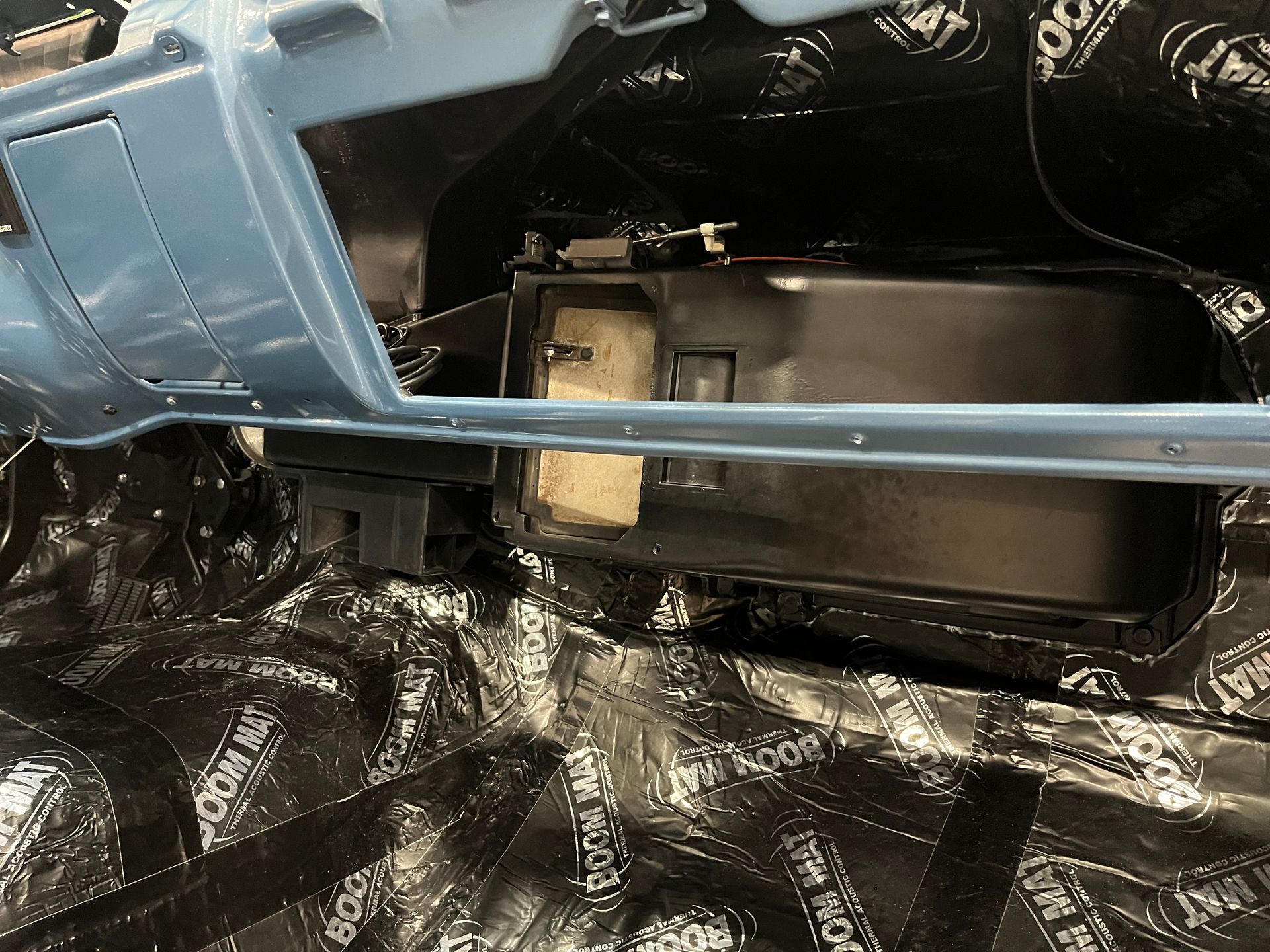 A blue car is sitting on top of a black tarp.