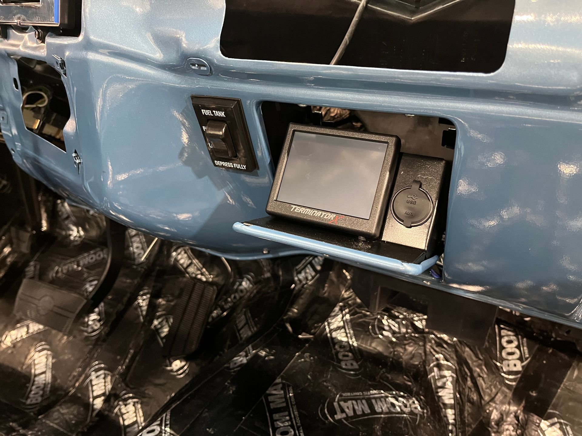 A blue car is sitting on top of a black mat.