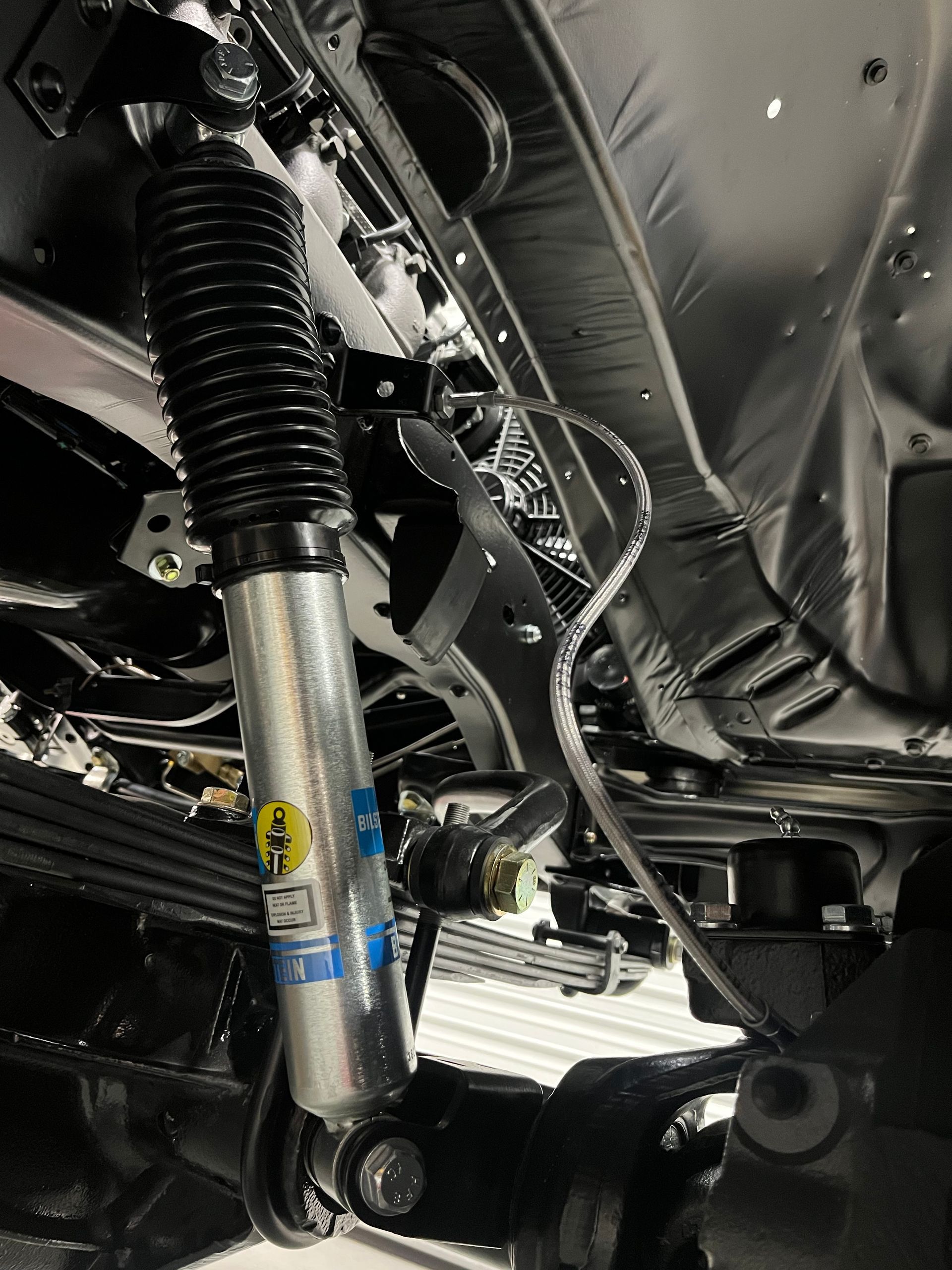 A close up of a shock absorber on the underside of a car.