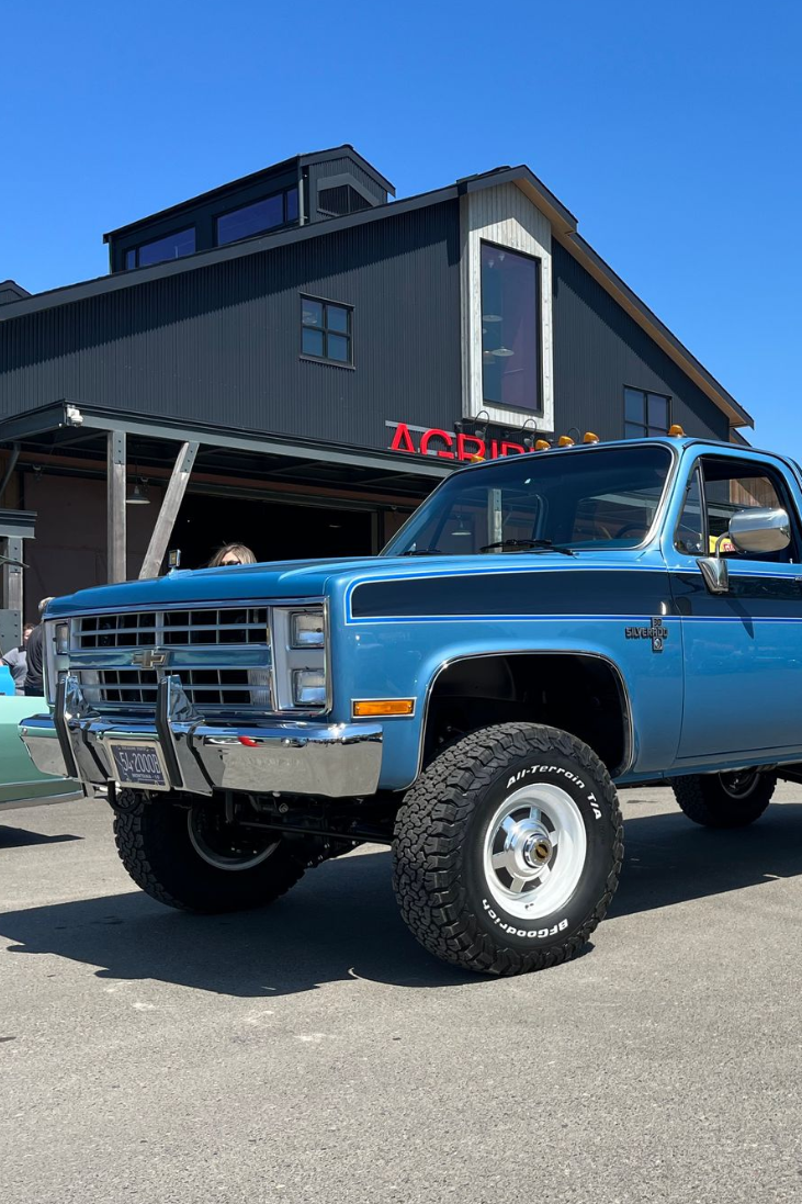 A man is working on a blue truck in a garage.