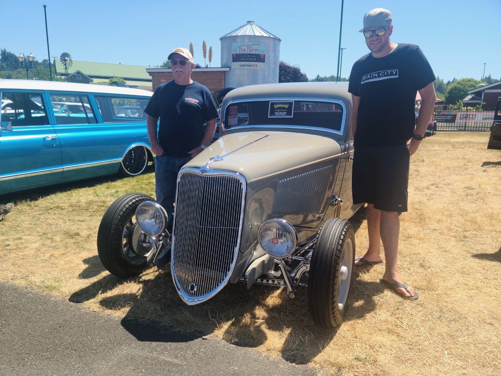 Two men are standing next to a car that has a zebra print on the front