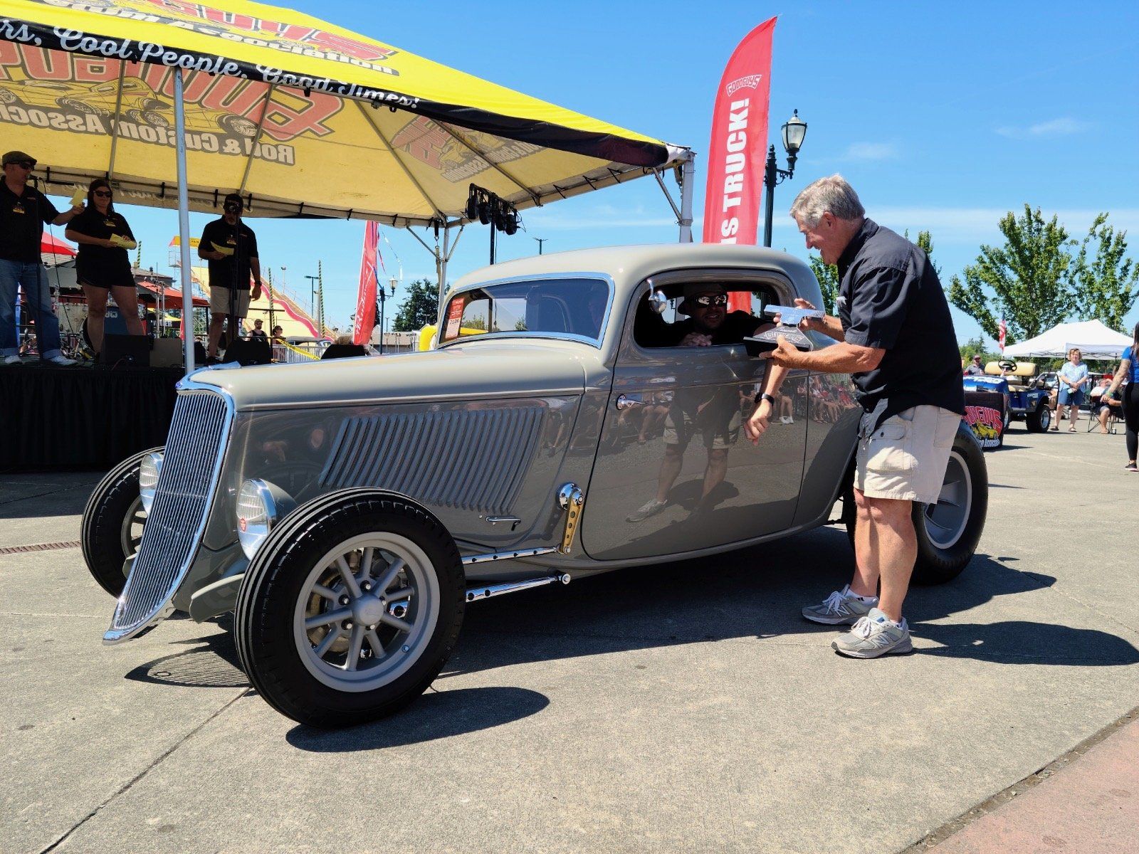 A man standing next to a car with a red flag that says trucks on it