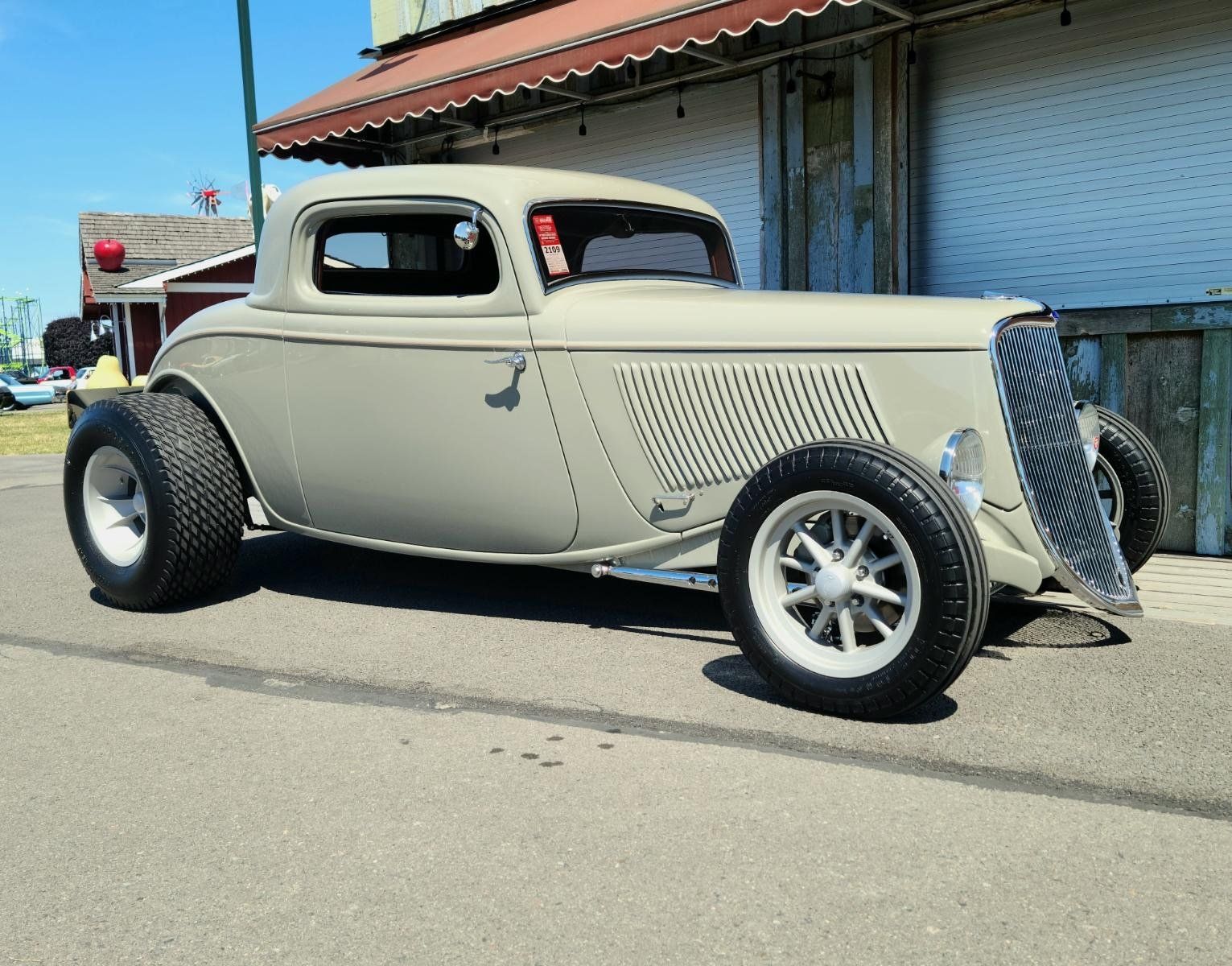 A classic car is parked on the side of the road in front of a building.