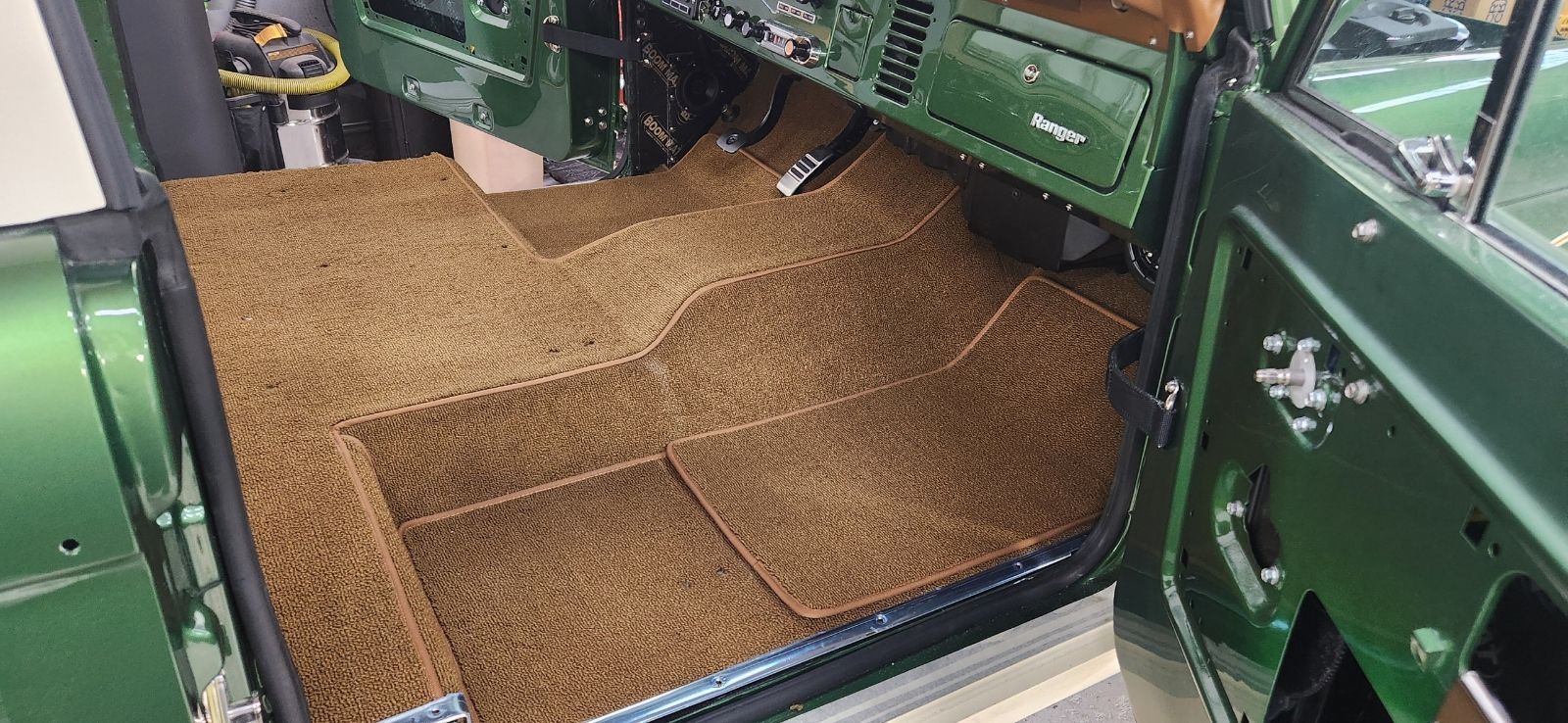 The interior of a green jeep with a brown mat on the floor.