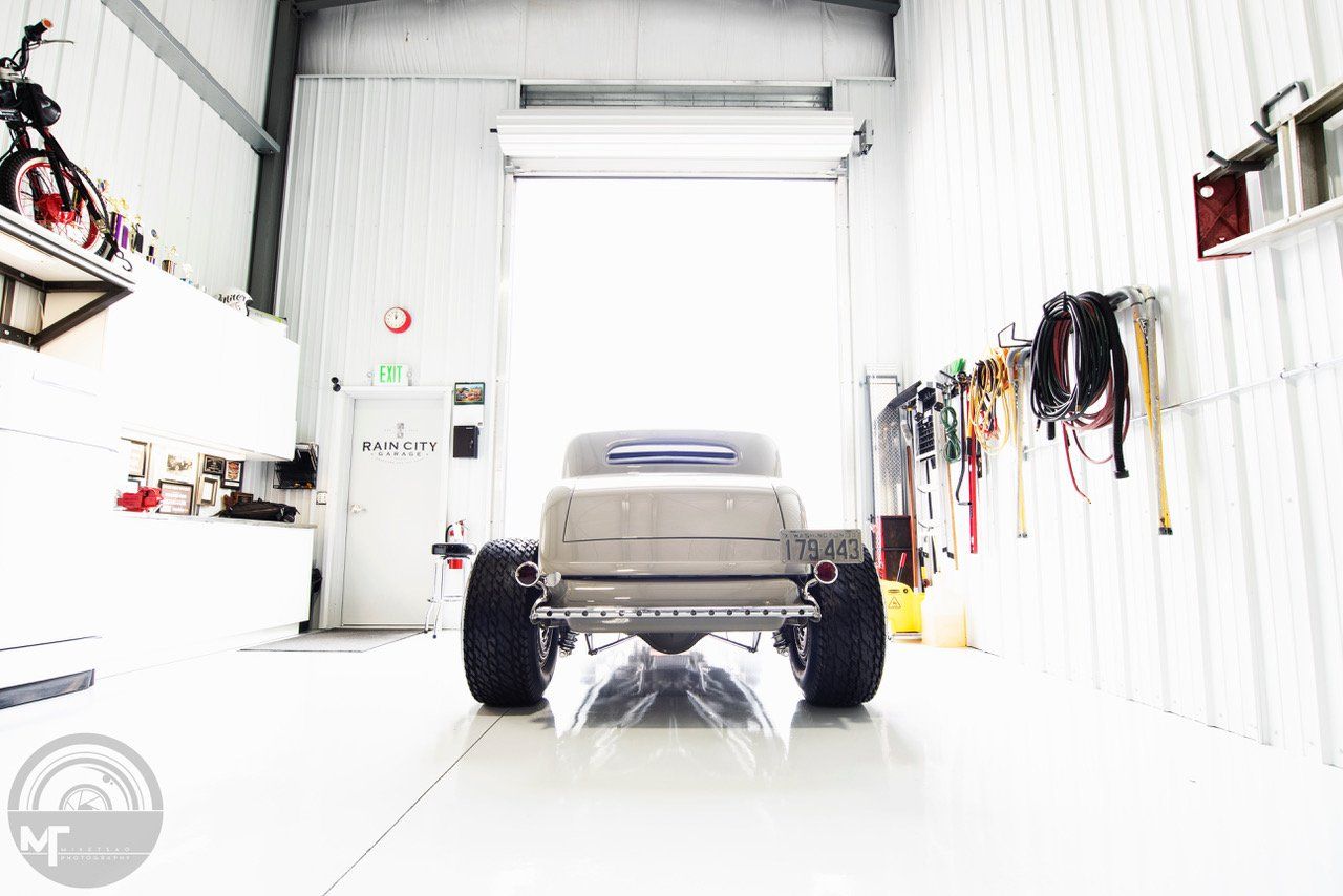 A white truck is parked in a garage with a large garage door.