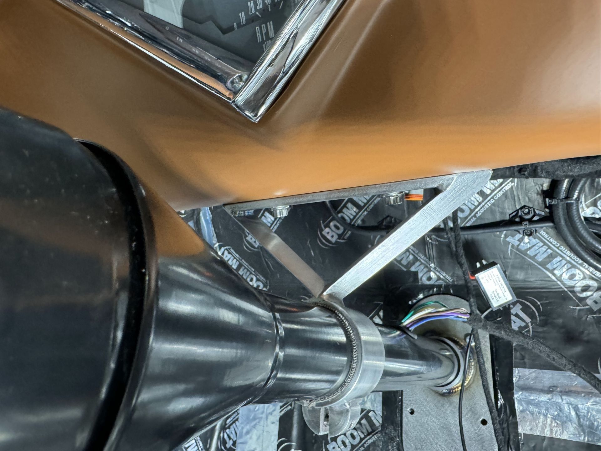 A close up of a car 's exhaust pipe and a steering wheel