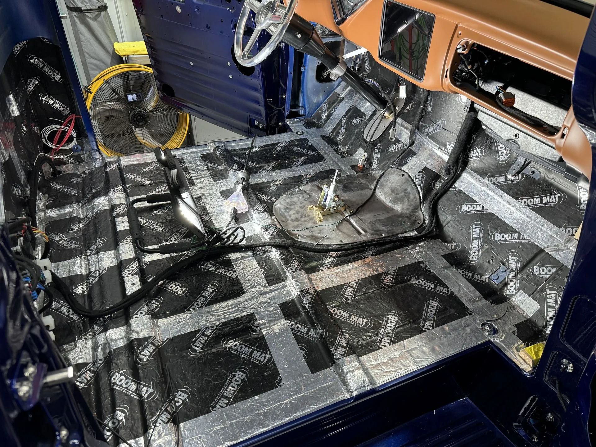 The inside of a car with a fan and a steering wheel.