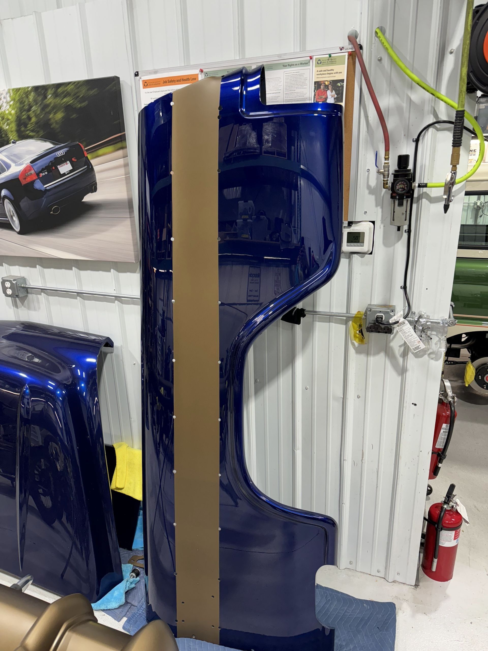 A blue truck fender is wrapped in cardboard in a garage